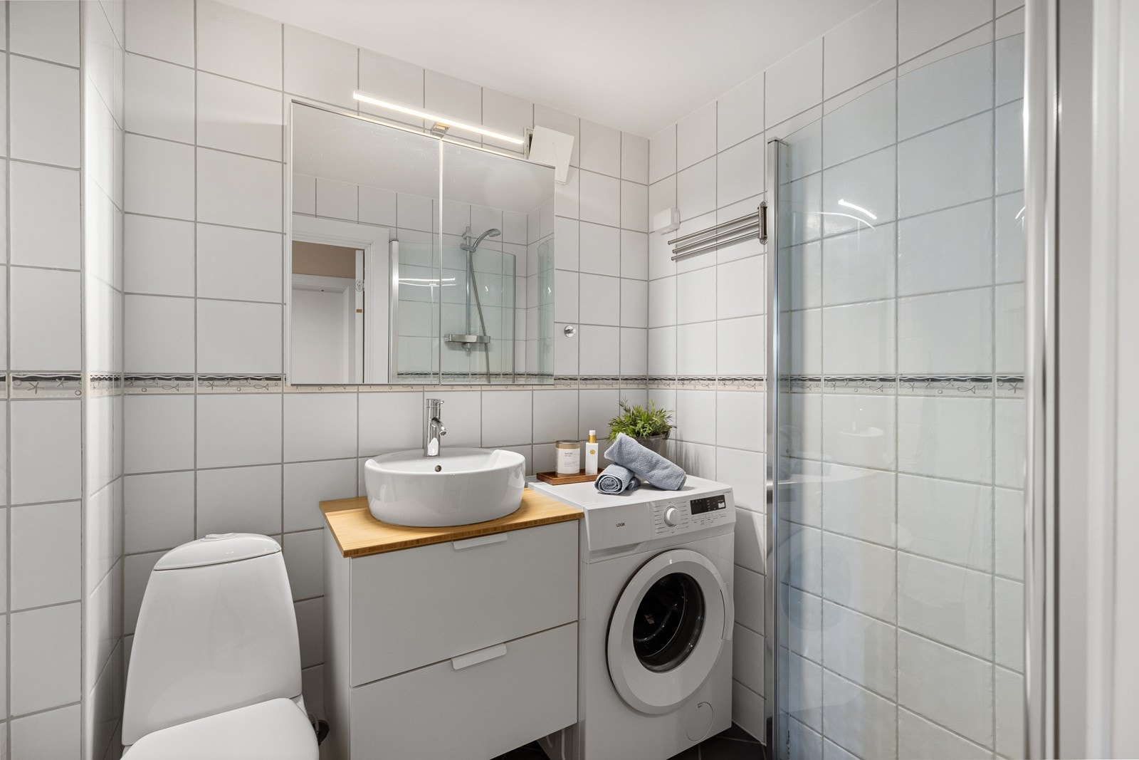 Badet er oppusset av borettslaget i 2004 og fremstår med lyse fliser på veggene og mørke fliser på gulvet. Vaskemaskin medfølger. Galleribilde