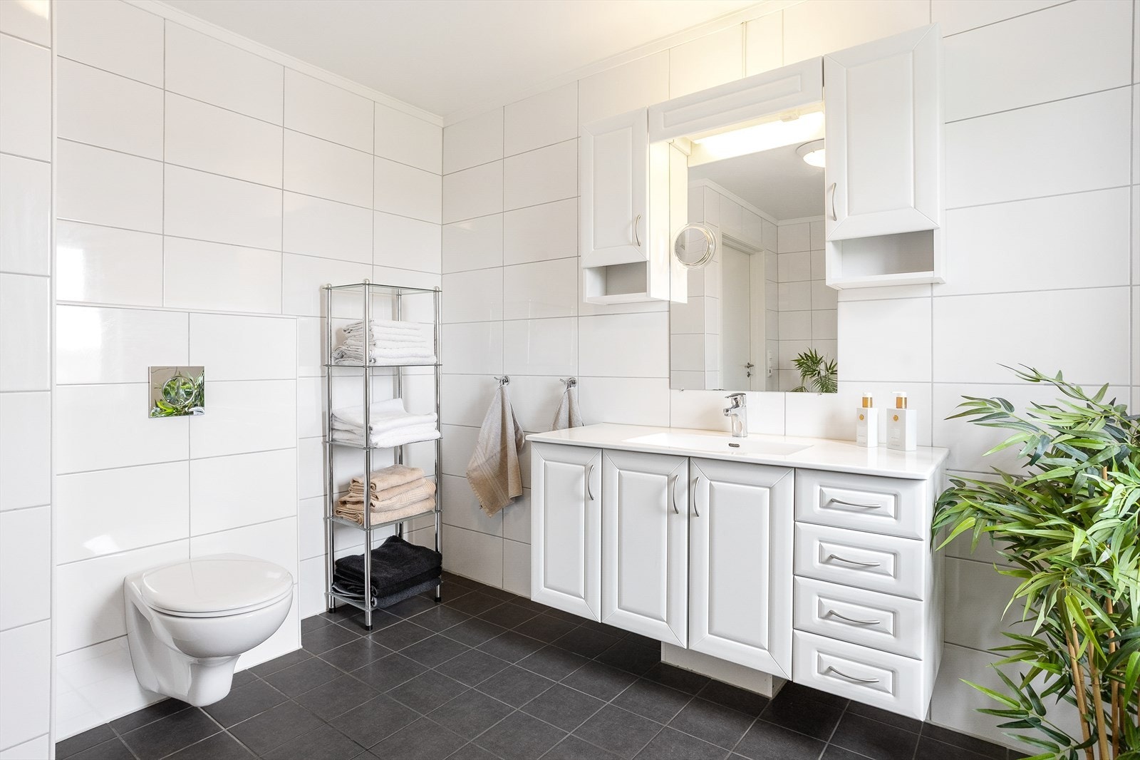 Badet har nedsenket dusjsone, vegghengt toalett og baderomsinnredning med servant og god oppbevaringsplass. Galleribilde