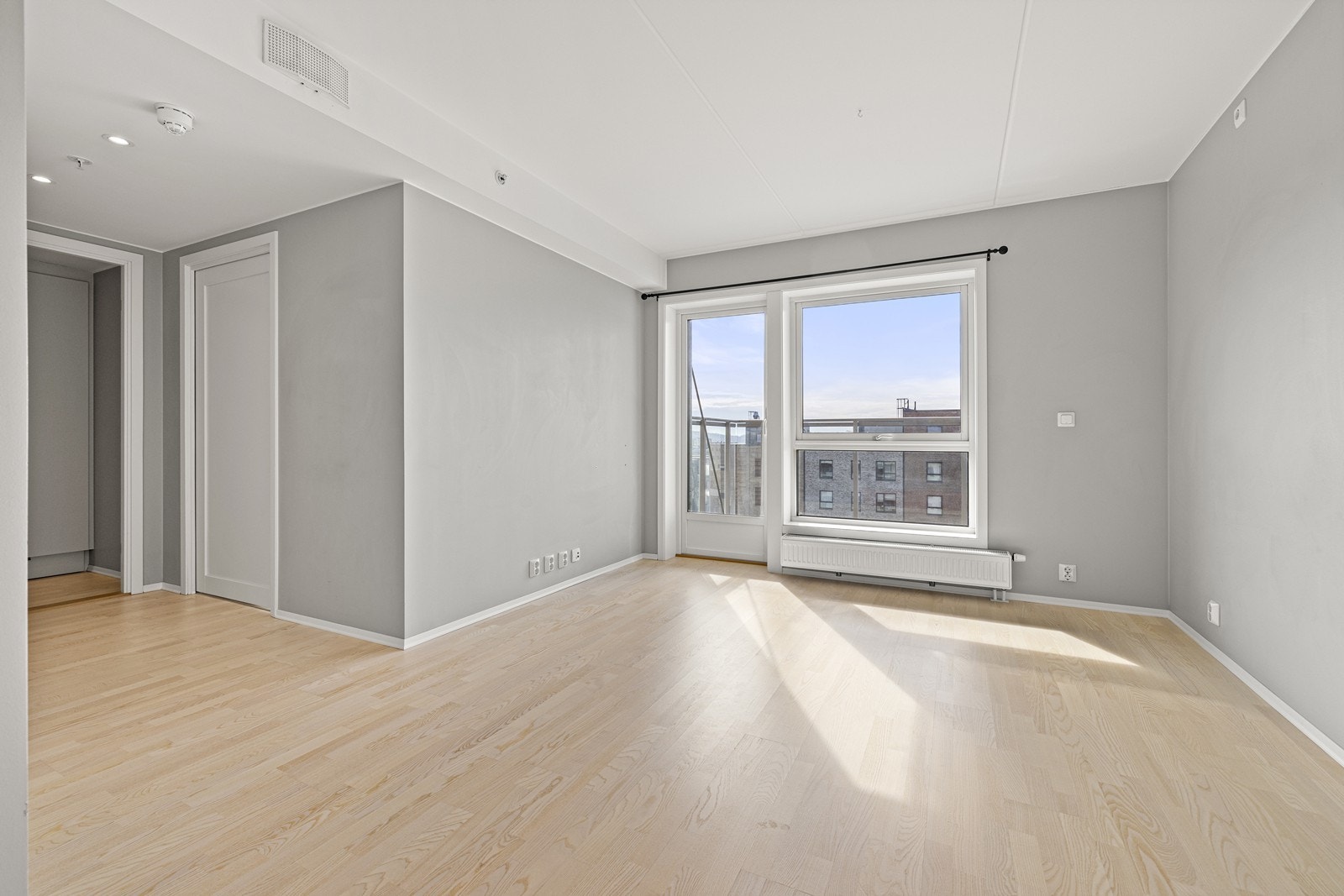 Leiligheten er malt i en elegant, lys gråtone og har store vindusflater som slipper inn rikelig med dagslys. Galleribilde