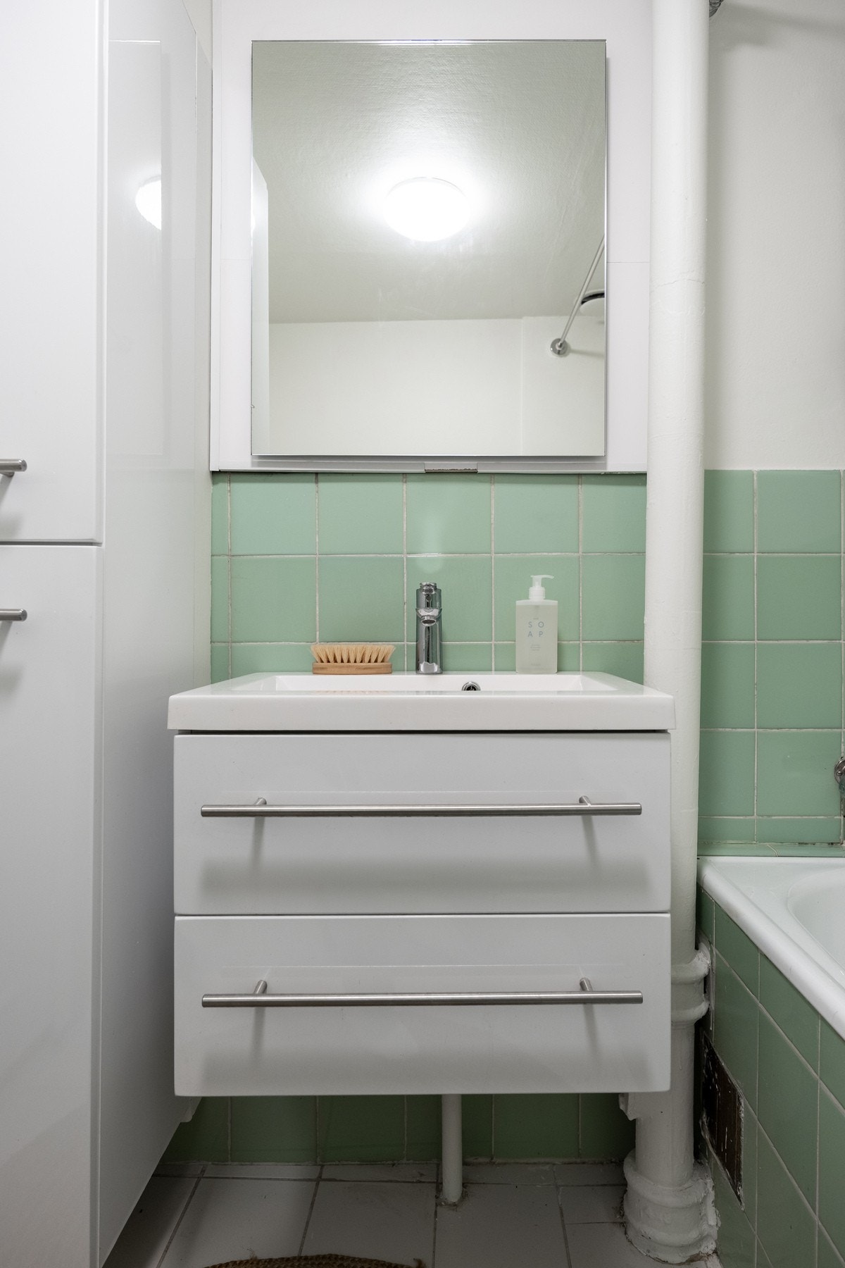 Badet er innredet med vegghengt servant med høyglans fronter og ovenpåliggende servant med ett-greps armatur, vegghengt speil over servant, innmurt badekar, samt gulvstående toalett. Galleribilde