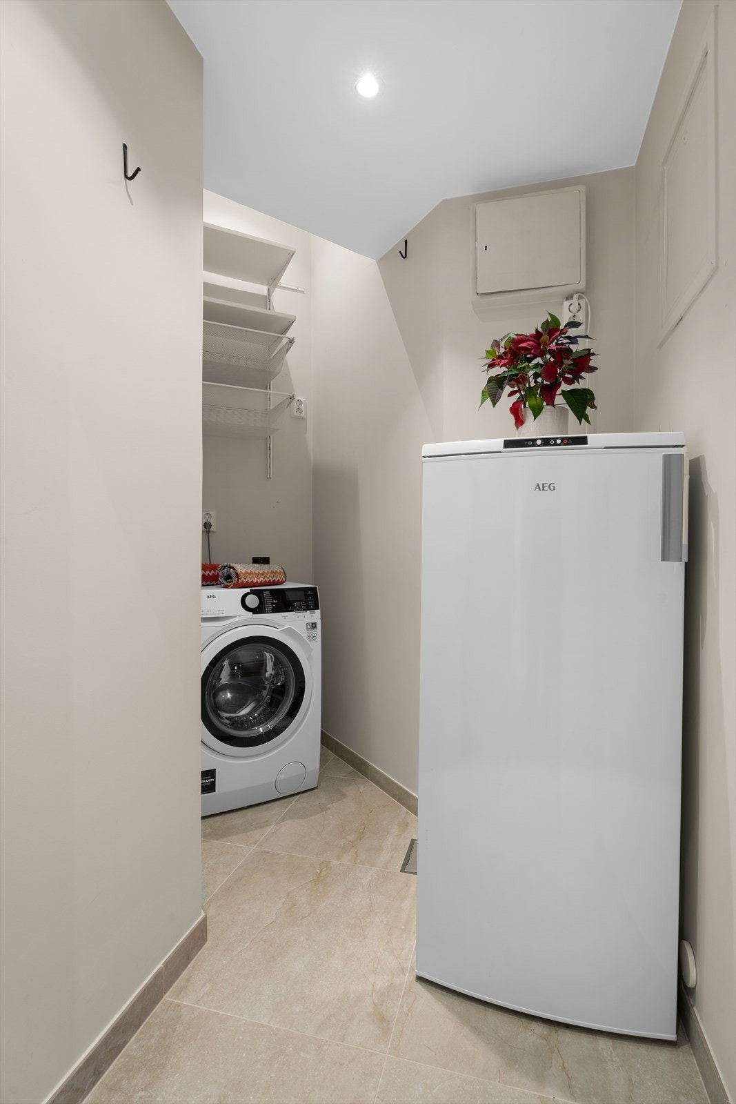 Vaskerom med flislagt gulv, varmekabler, sluk og svært praktisk plassering midt i leiligheten, rett ved kjøkkenet. Rommet har også plass til fryseskap og ekstra lagring. Galleribilde