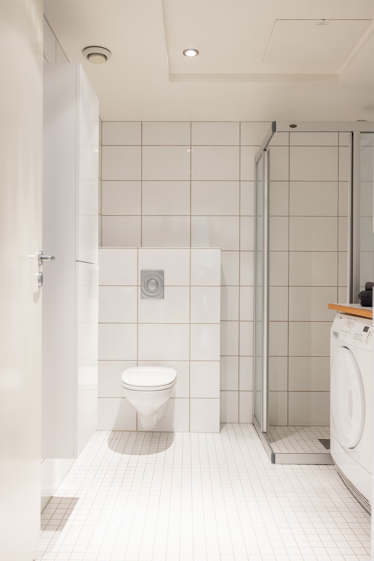 Badet består av vegghengt toalett, dusjhjørne, servant over innredning og speil. Galleribilde