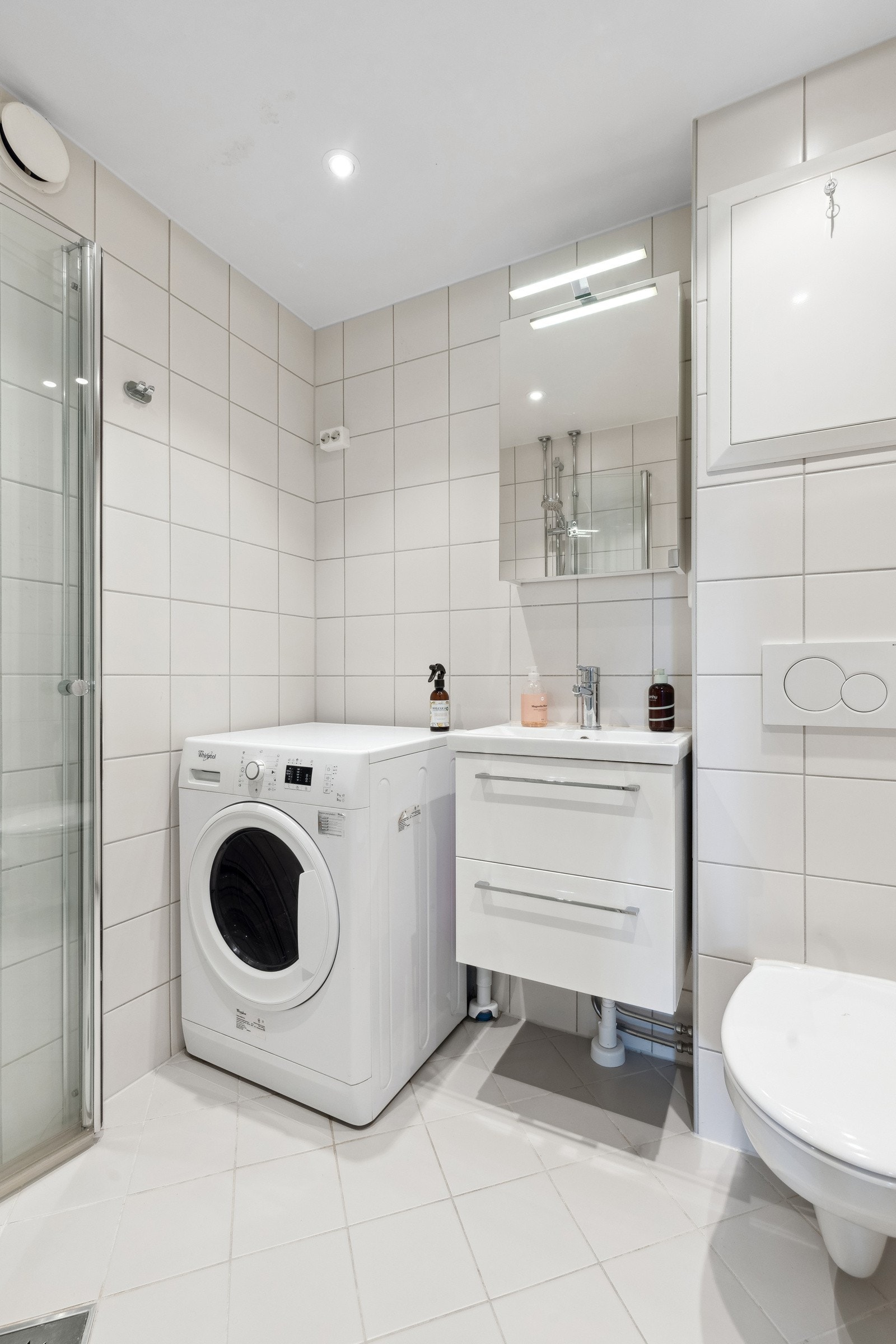 Moderne servant med innredning og overskap med speil. Vegghengt toalett. Dusj med skyveglass. Vaskemaskin vil følge leiligheten. Galleribilde