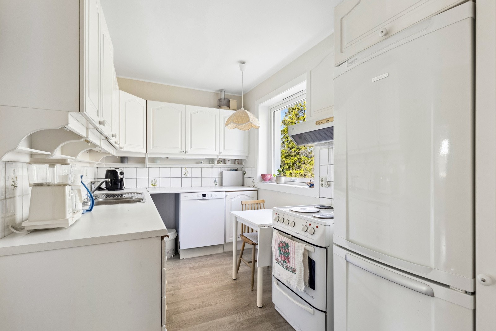 Lyst kjøkkenrom med hyggelig spiseplass ved vinduet. Galleribilde