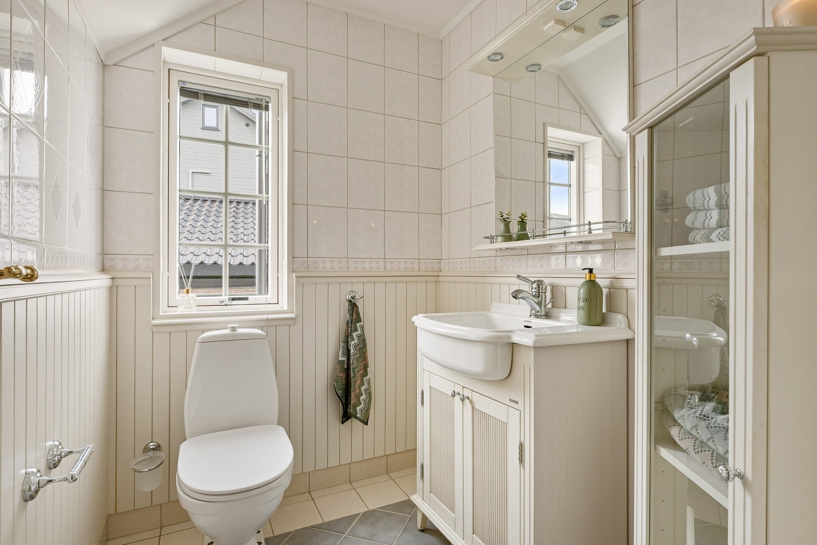 Badet beliggende innenfor gangen er bygget opp med fliser på gulv med varme og delvis fliser kombinert med brystpanel på vegger. Galleribilde
