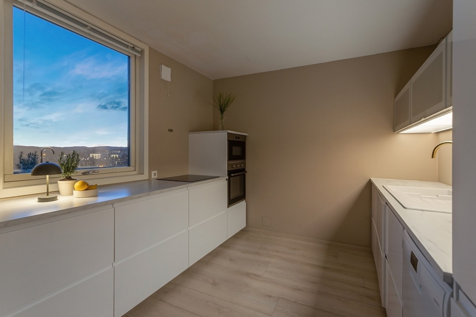 Kjøkkeninnredningen er fra 2018/2019 og består av hvite, glatte fronter. Belysning under overskap. Laminat benkeplate med nedfelt kum. Galleribilde