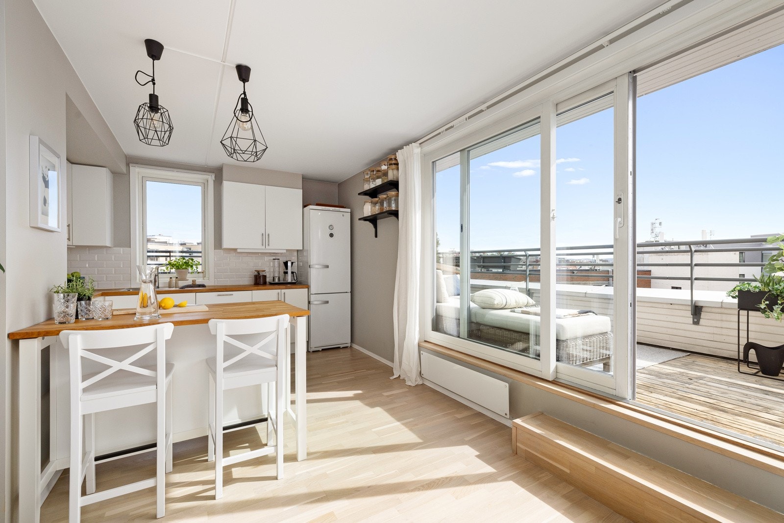 Pen og moderne kjøkkeninnredning fra 2006. Innredningen har hvite glatte fronter og heltre benkeplate med nedfelt oppvaskkum Galleribilde