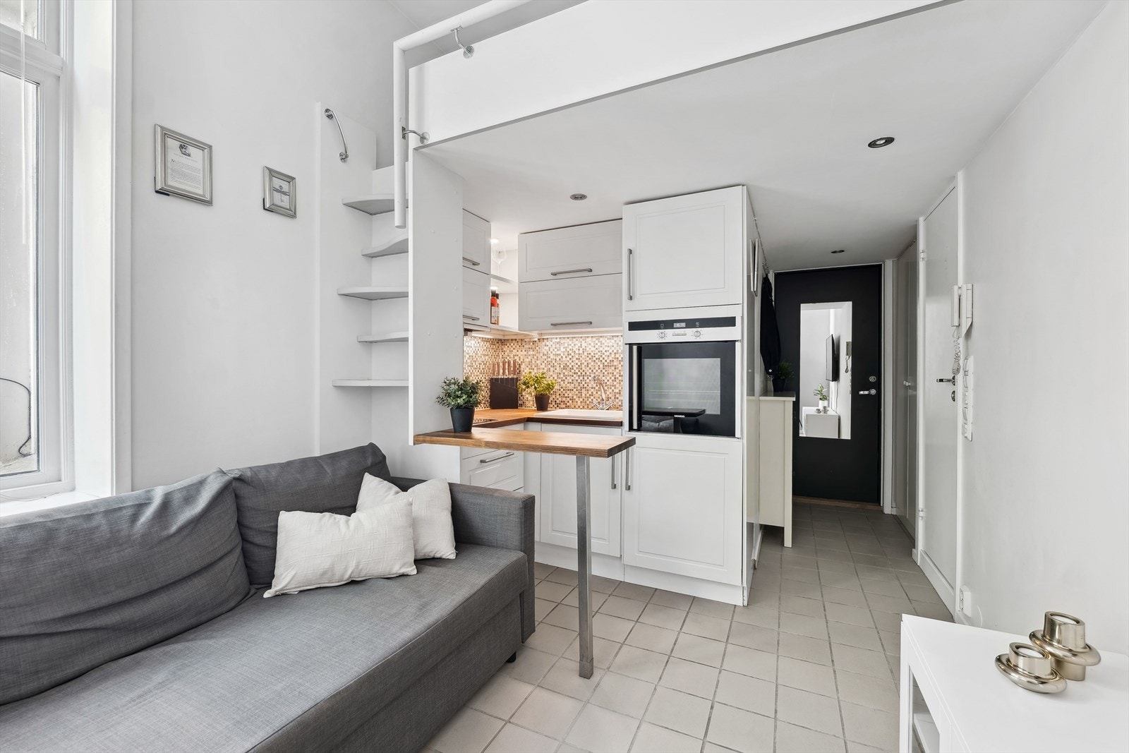 Leiligheten har en åpen stue/kjøkken løsning med plass til sofa, tv-løsning og møbler for oppbevaring. Galleribilde