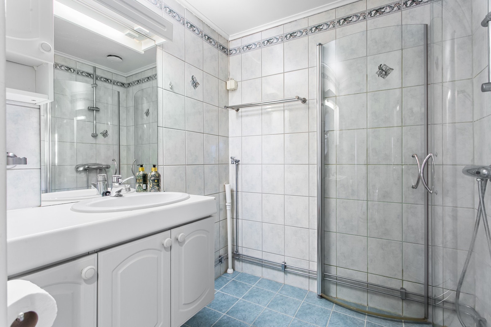 Dusjhjørne med buede glassdører og opplegg for både vaskemaskin og tørketrommel. Galleribilde