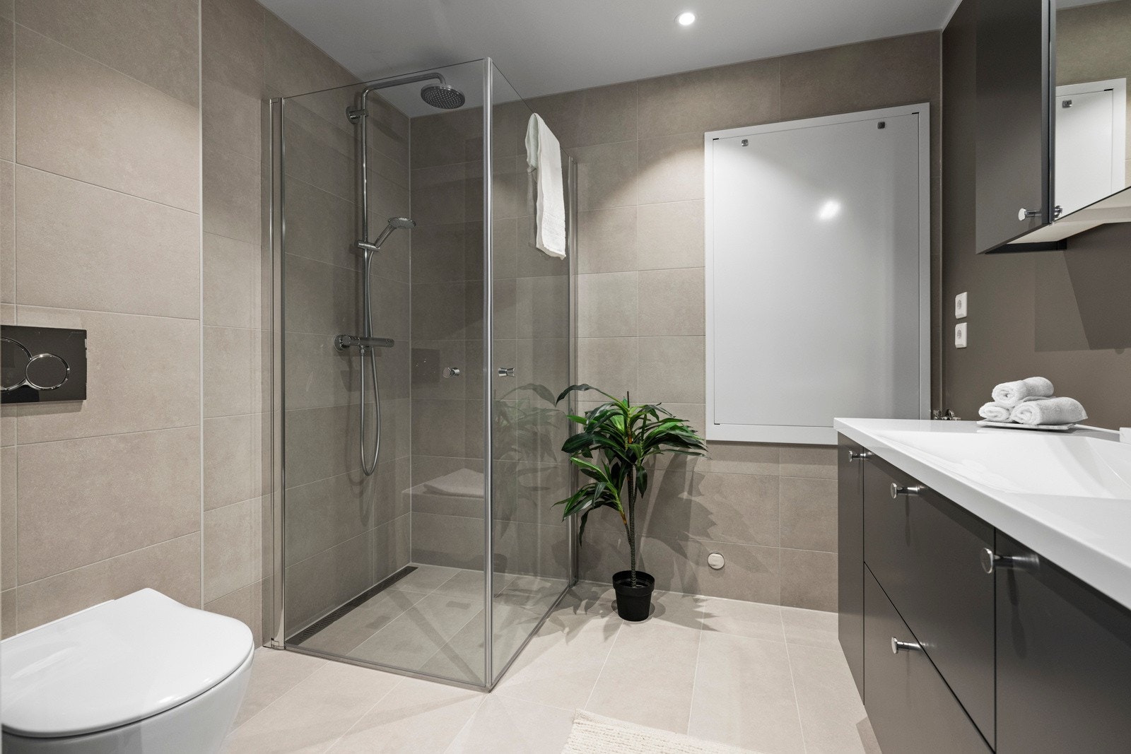 Badet inneholder veggmonterte dusjdører, servant med underskap, speil, opplegg for vaskemaskin og veggmontert wc. Dette er et herlig sted å starte dagen! Galleribilde