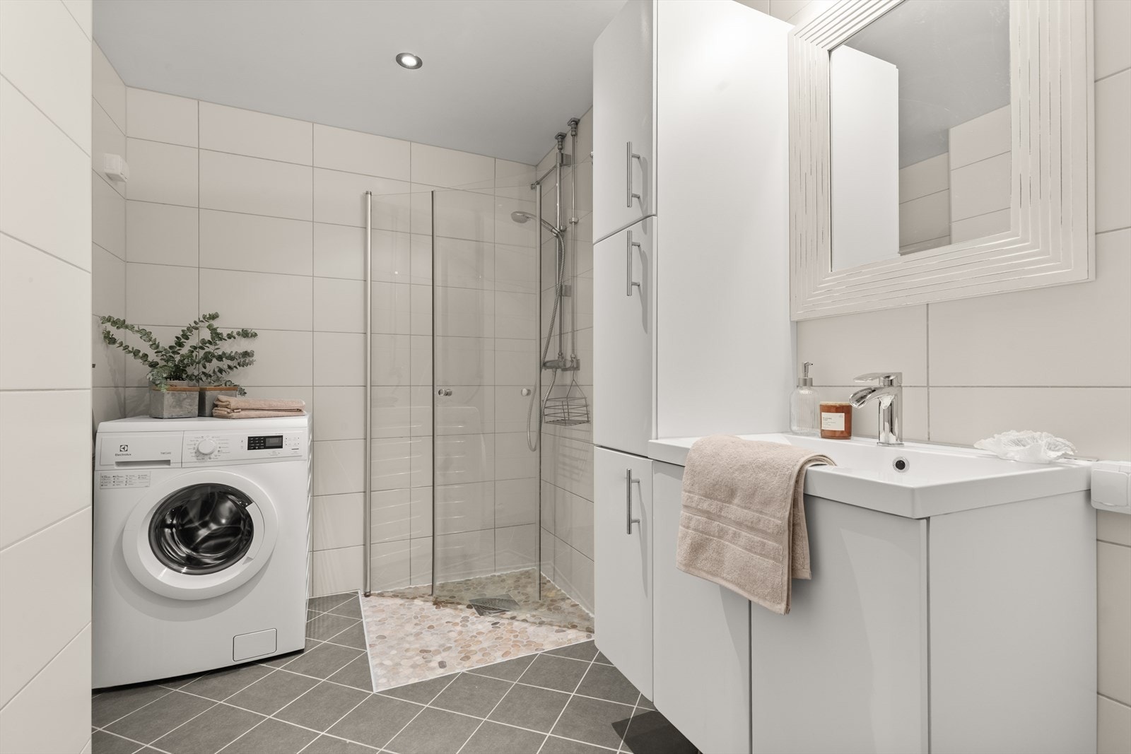 Pent og lyst flislagt baderom i regi av borettslaget fra 2013. Badet er av god størrelse med stor, innfellbar dusjnisje, baderomsinnredning, vegghengt wc, varmekabler og opplegg for vaskemaskin og tørketrommel. Galleribilde