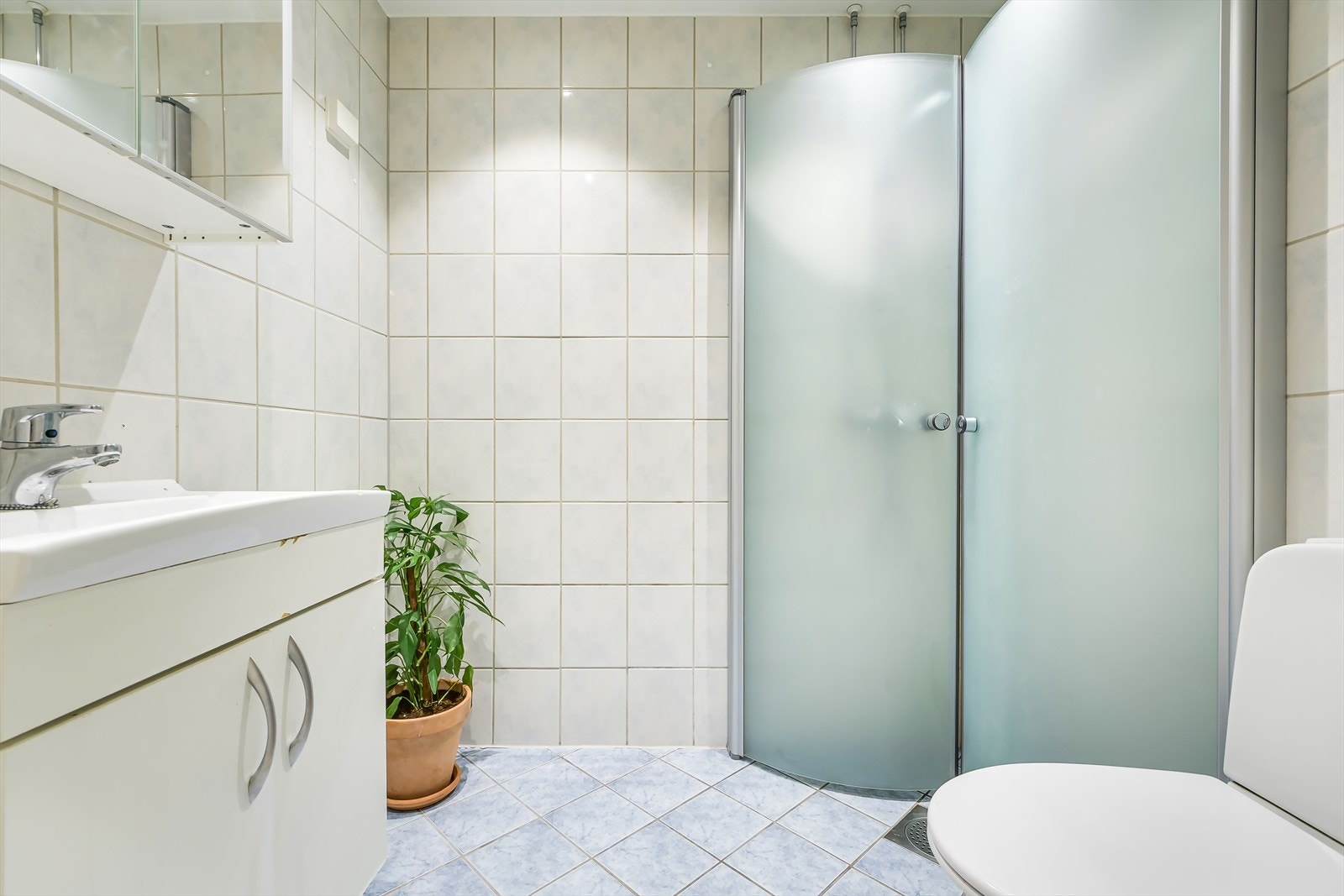 Badet er innredet med servantskap, dusjsone, toalett og opplegg for vaskemaskin Galleribilde