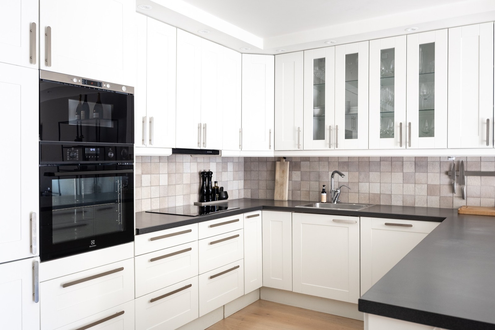 Fliser mellom kjøkkenbenk og overskap samt stikkontakter og benkeskapsbelysning. Galleribilde