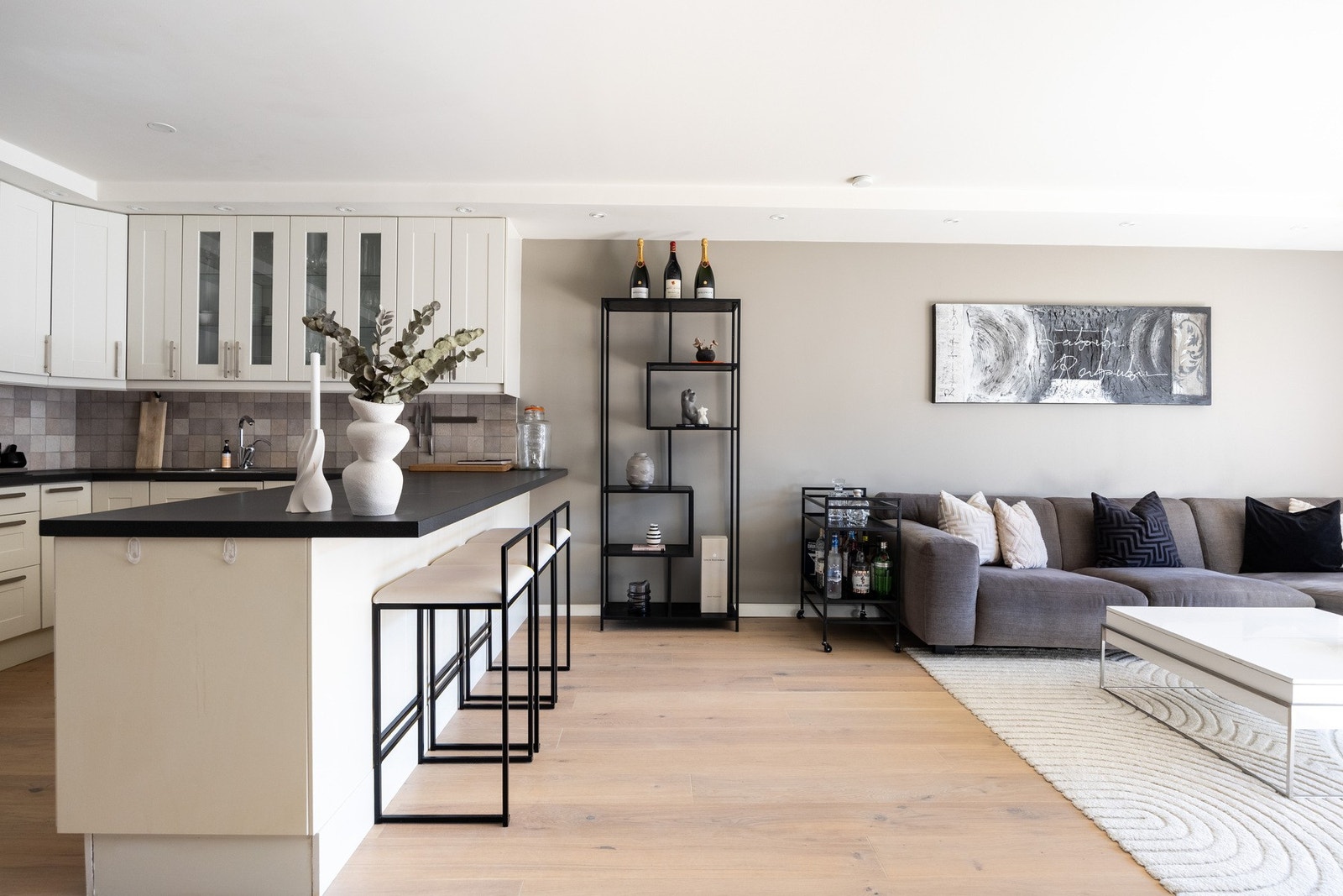 Stor kjøkkenøy med plass til barstoler som lager en naturlig oppdeling av rommet. Galleribilde