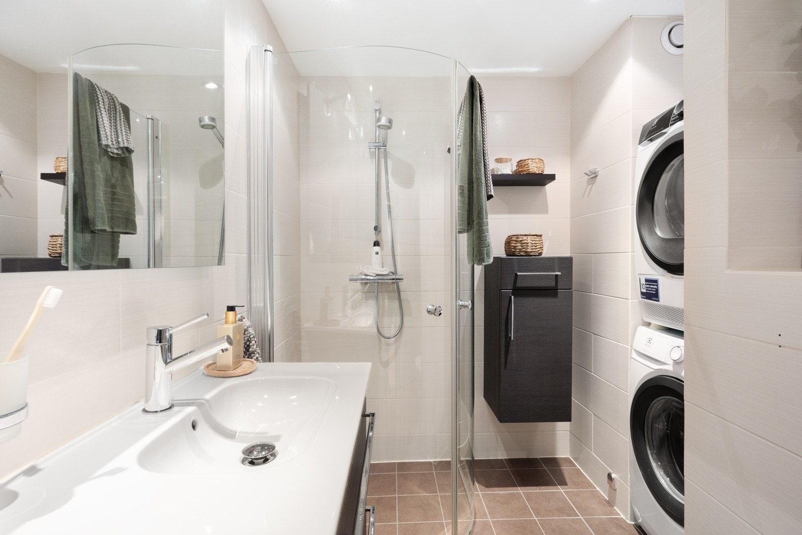 Flislagte overflater i lune fargetoner, downlights og gulvvarme, samt opplegg for vaskesøyle. Galleribilde