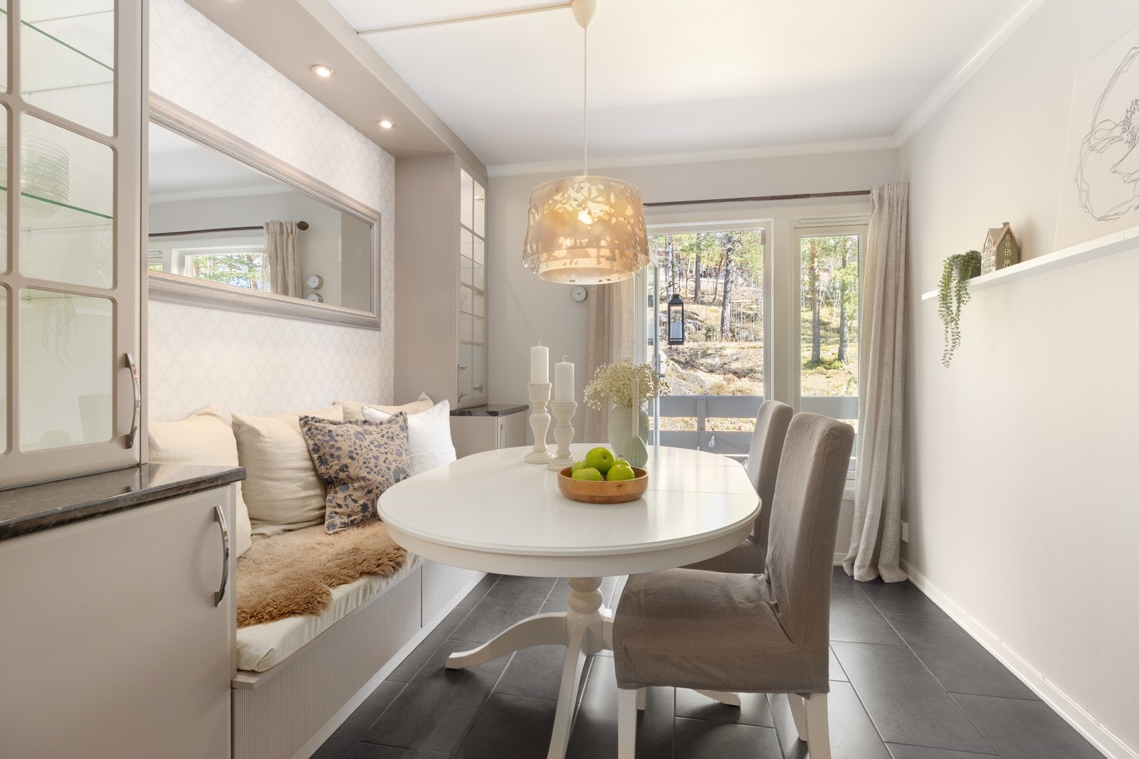 Pent og hyggelig kjøkken med spiseplass, plassbygd benk, belysning og vitrineskap som skaper både atmosfære og funksjon. Galleribilde