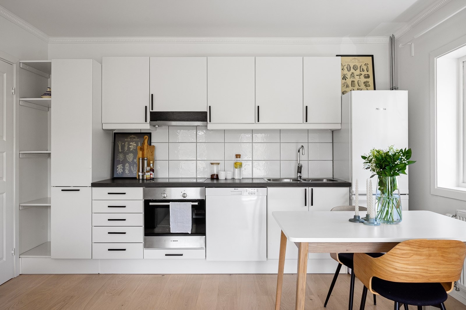 Kjøkkenet har fabrikklakkerte fronter, nedfelt kum i rustfritt stål og fliser mellom benk og overskap. Galleribilde