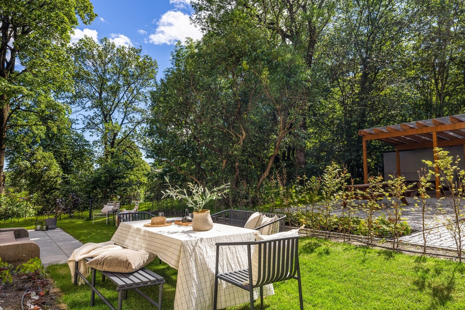 Eiendommen er tilbaketrukket og omkranset av løvtrær og frodig vegetasjon Galleribilde