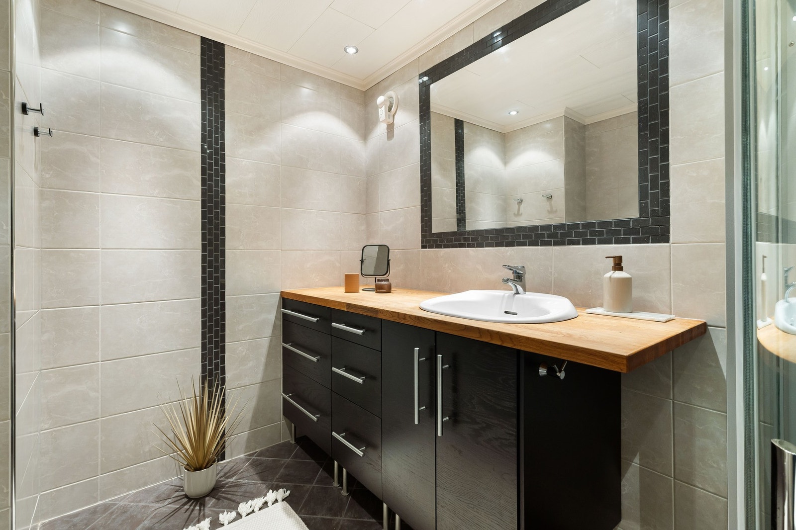 Baderomsinnredningen består av vegghengt toalett, helstøpt servant, skap under servant med slette fronter, dusjdører i klart glass. Galleribilde