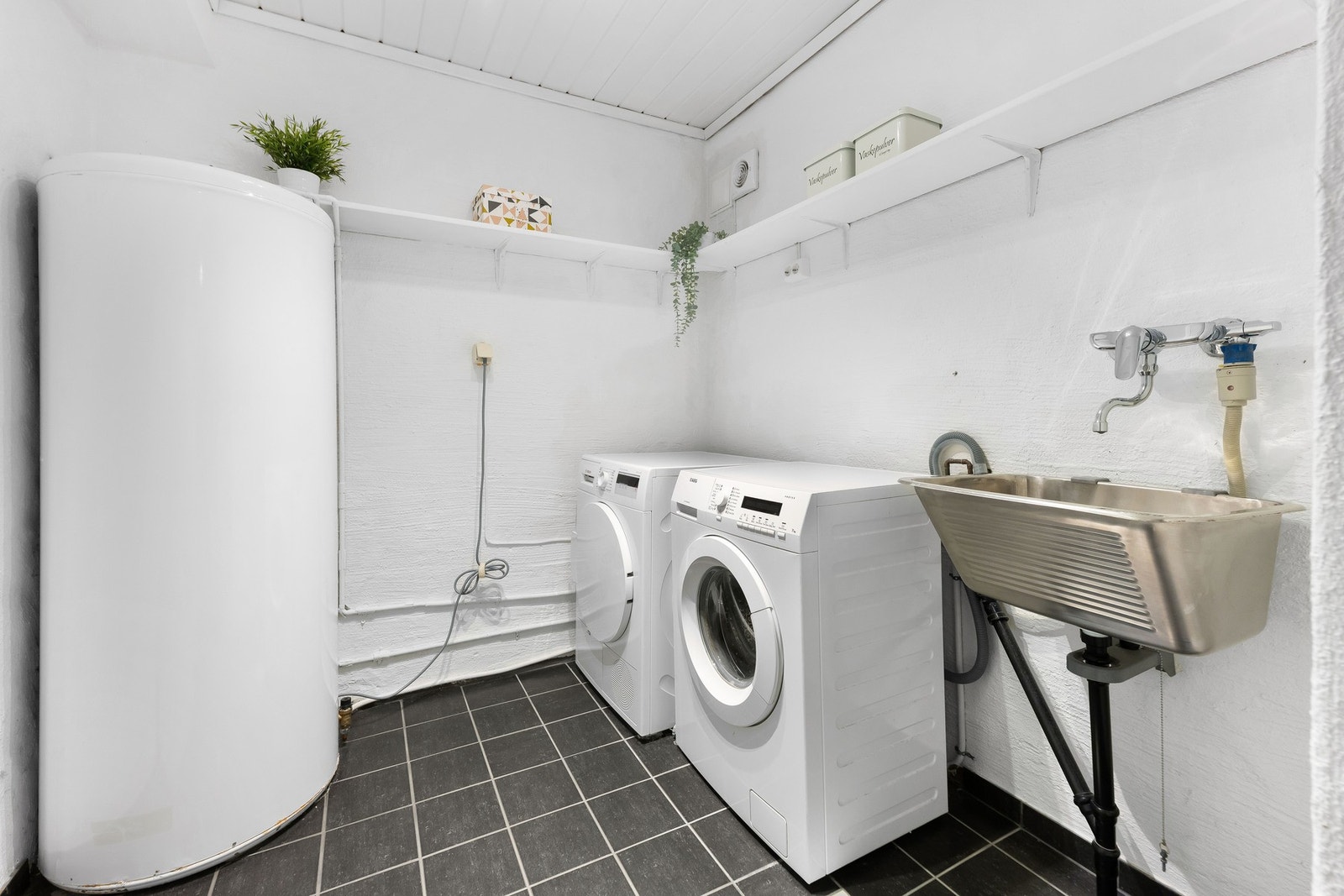 Romslig vaskerom med opplegg for vaskemaskin og tørketrommel, utslagsvask, varmtvannsbereder, samt fordelerskap til rørsystemet. Galleribilde