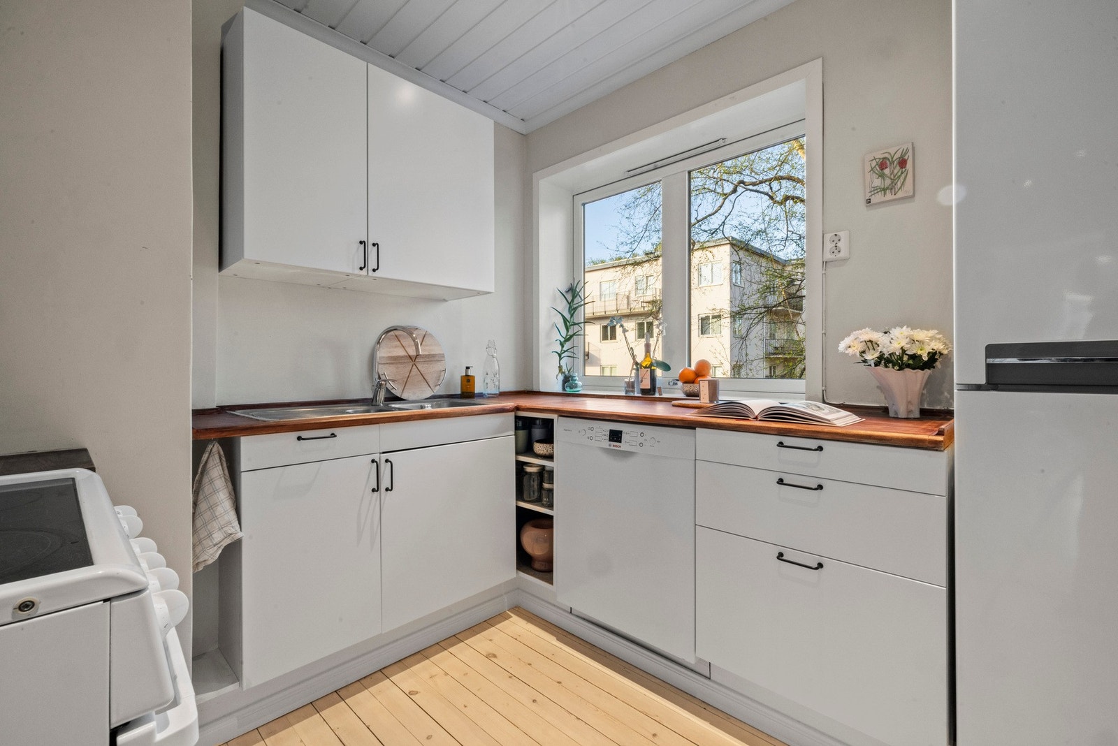 Kjøkkenet er separat og lyst. Med tidløs og klassisk hvite, glatte fronter og benkeplate i tre med nedfelt oppvaskkum. Galleribilde