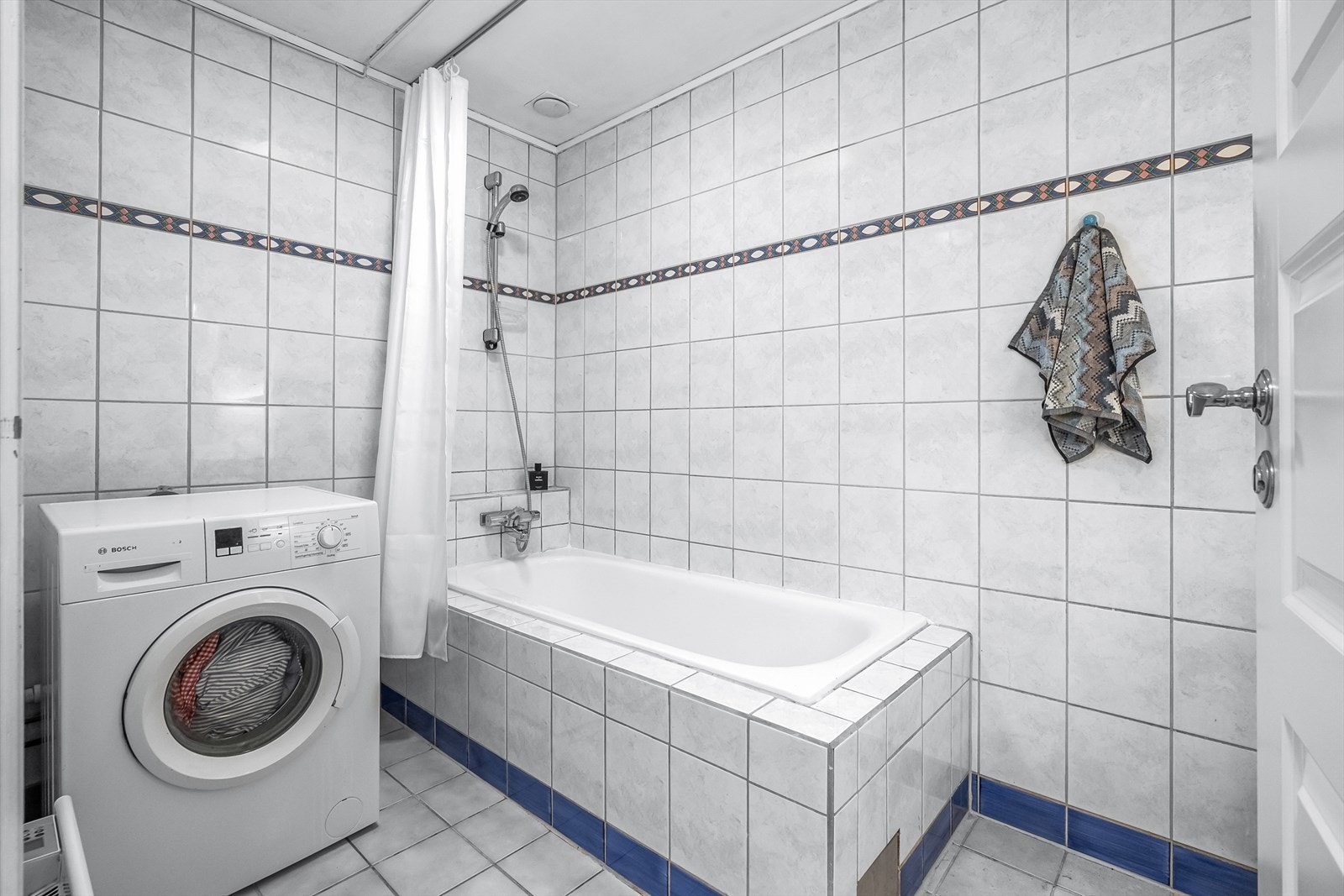 Badet er innredet med servant nedfelt i innredning, speilskap med lys og badekar. Det er opplegg for vaskemaskin og har naturlig avtrekk. Galleribilde