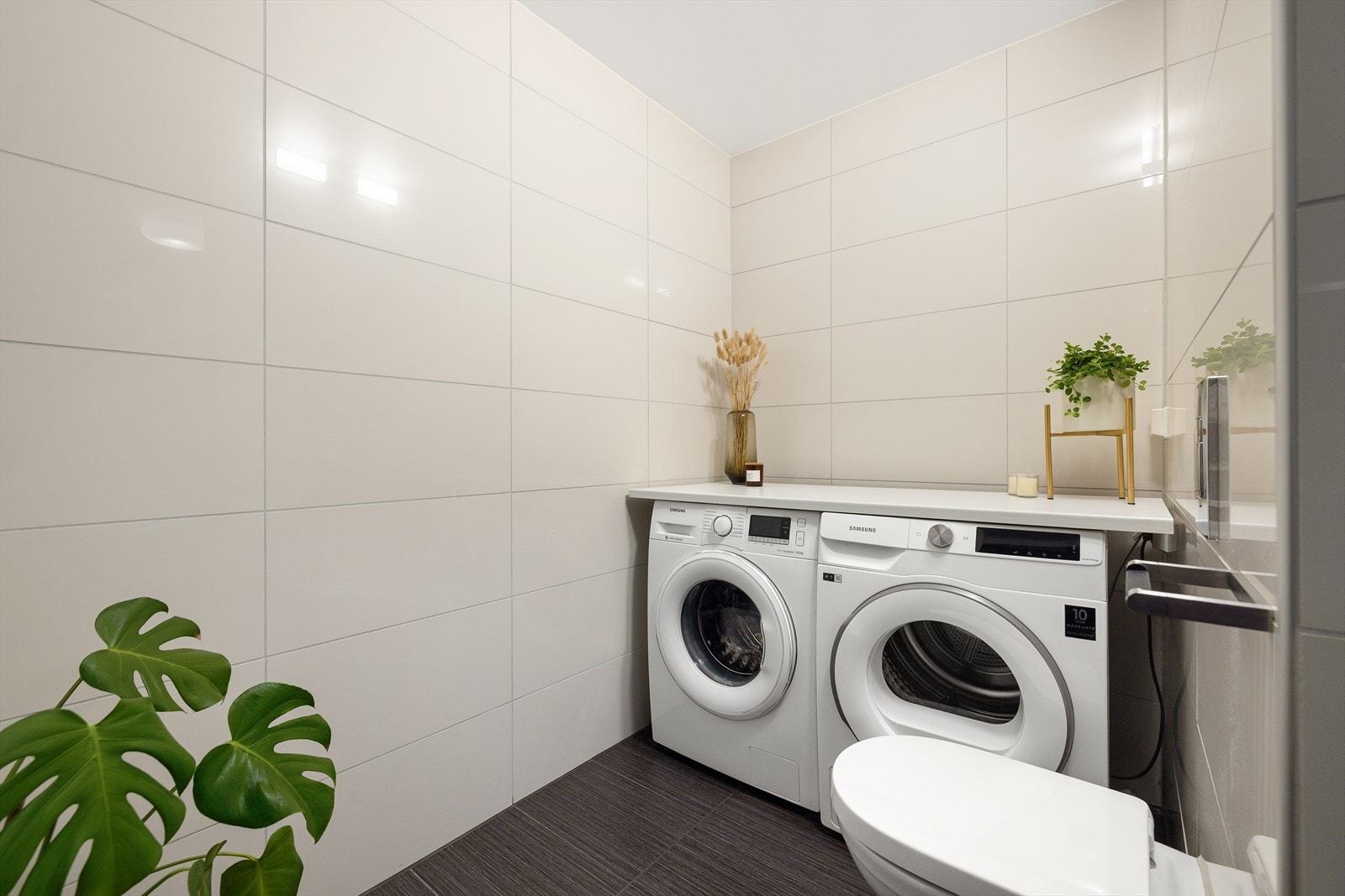 Opplegg og plass til vaskemaskin og tørketrommel under benkeplate bak vegg. God plass til å tørke klær e.l. på badet Galleribilde