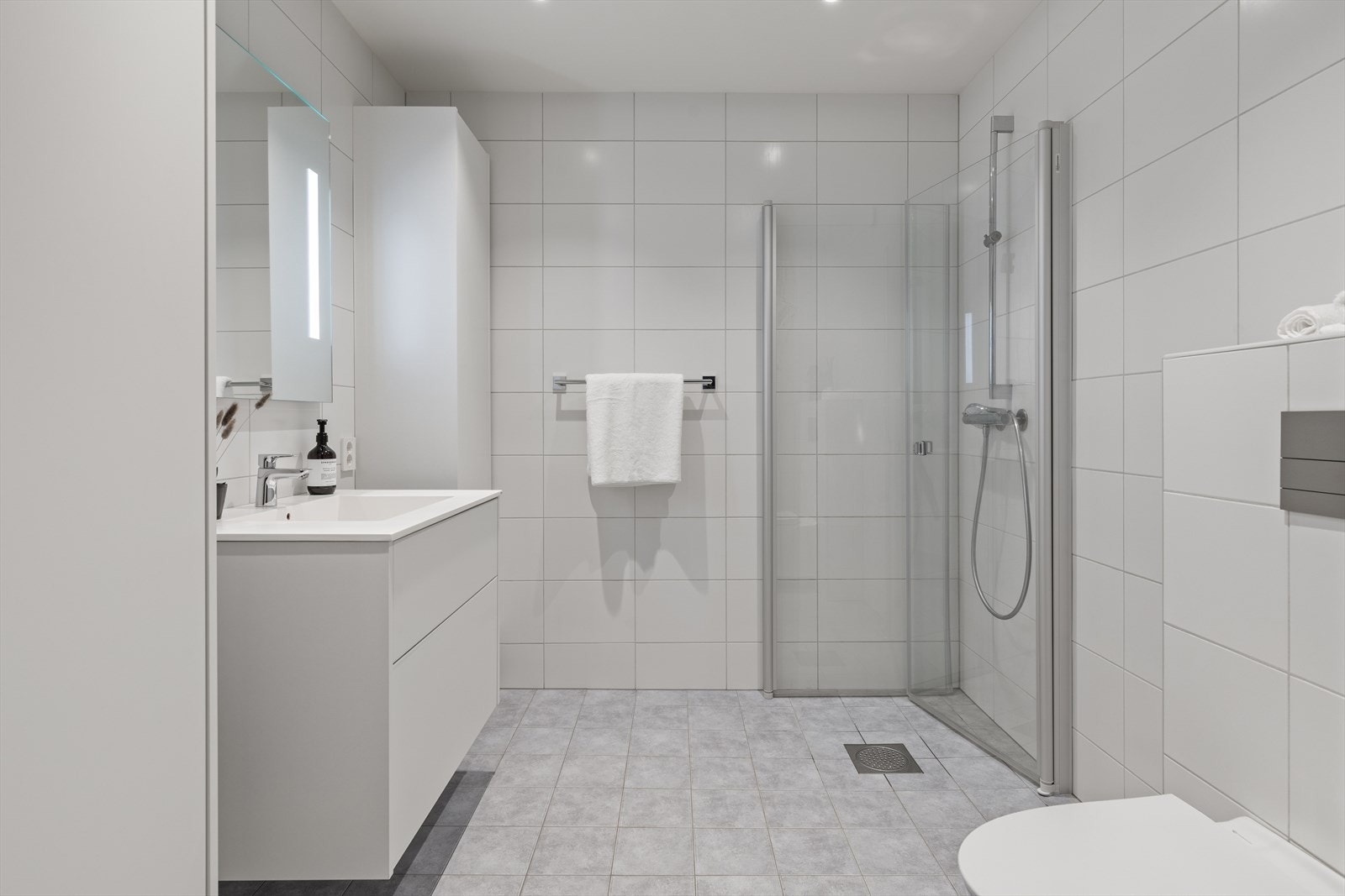 Det er to baderom i første etasje, denne ligger i østre del og er utstyrt med toalett, dusjhjørne og baderomsinnredning. Galleribilde