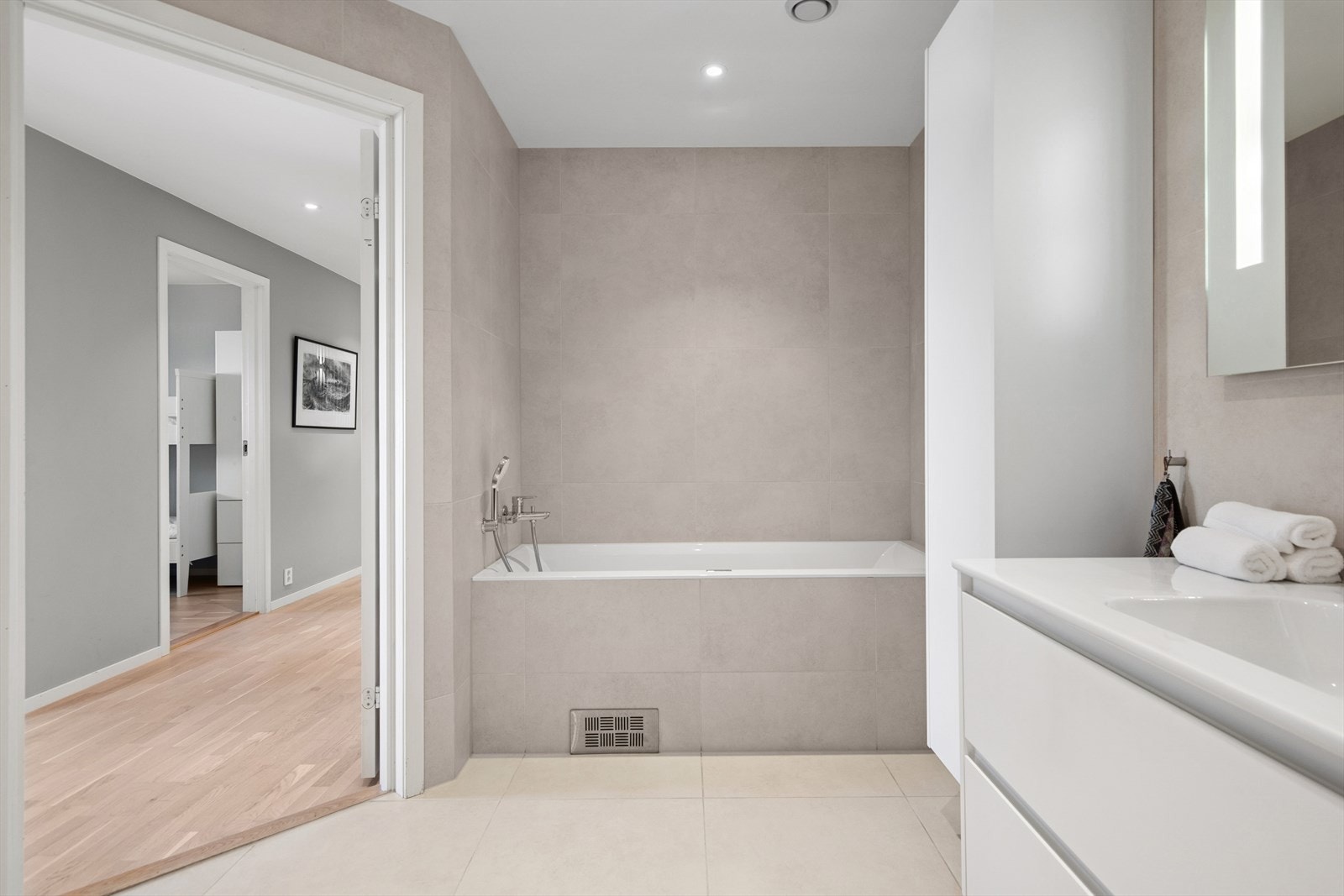 Flislagt i lys, behagelig fargetone og utstyrt med toalett, dusjhjørne, badekar og baderomsinnredning. Galleribilde