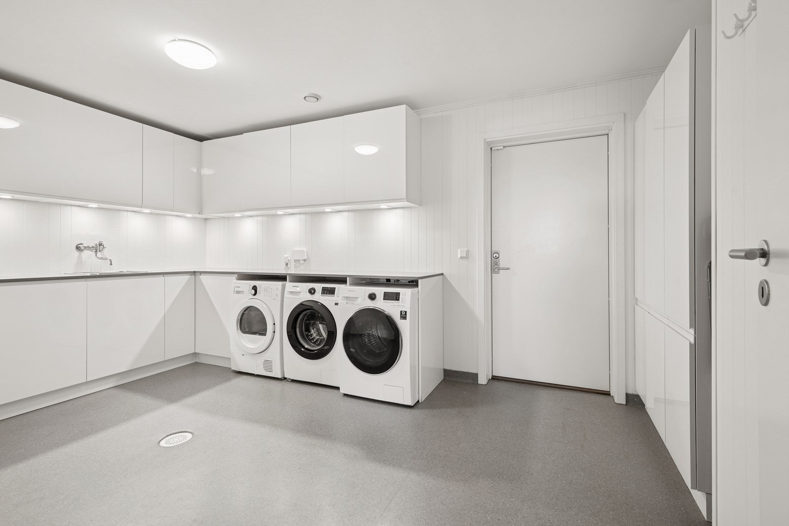 Praktisk med separat vaskerom, som her har rikelig av oppbevaringsplass samt rom for to vaskemaskiner og tørketrommel. Døren går til garasjen. Galleribilde