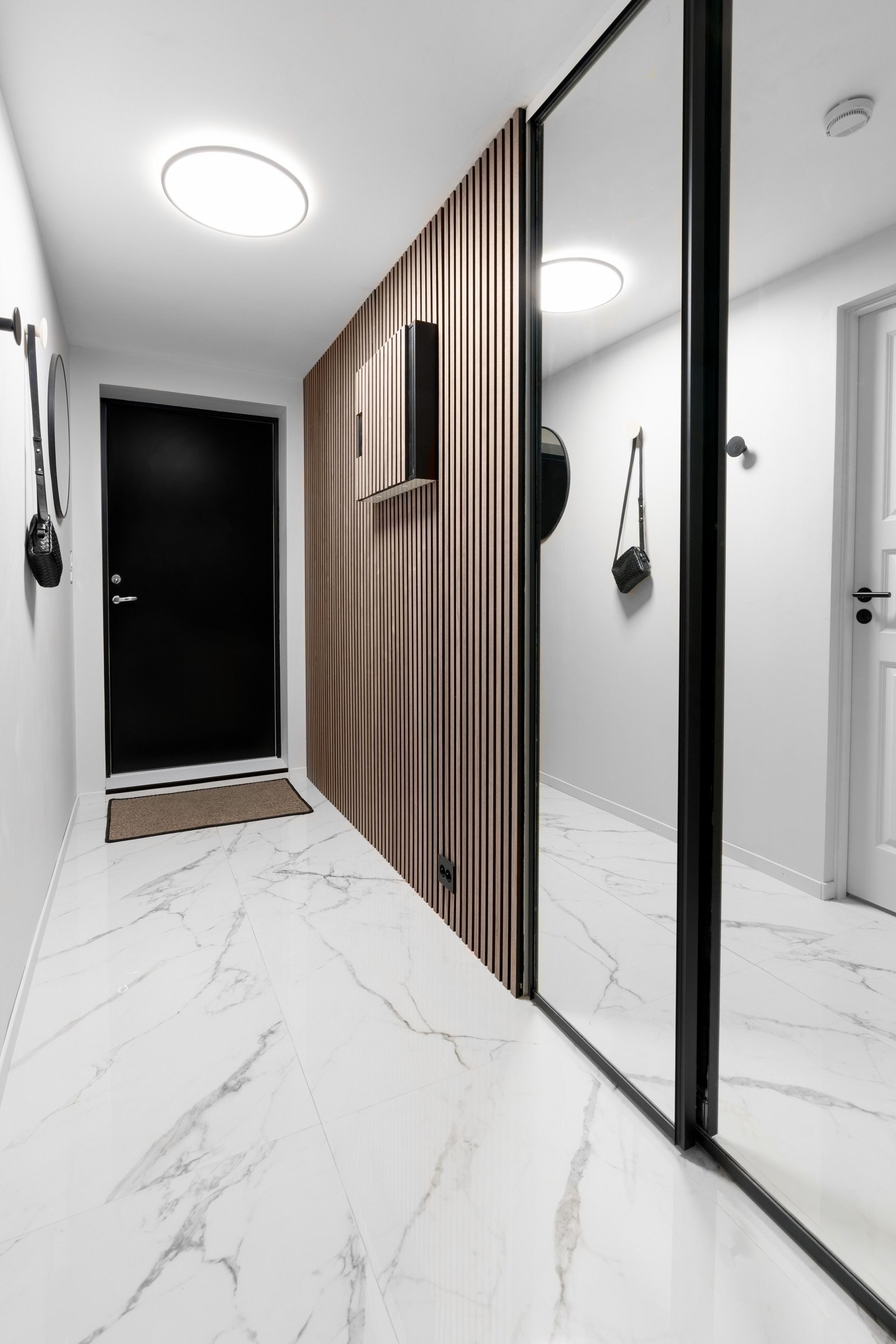 Lys og romslig entré med store fliser, listefrie vegger og spiler. Oppbevaring med skyvedørsgarderobe og varme i gulv. Galleribilde