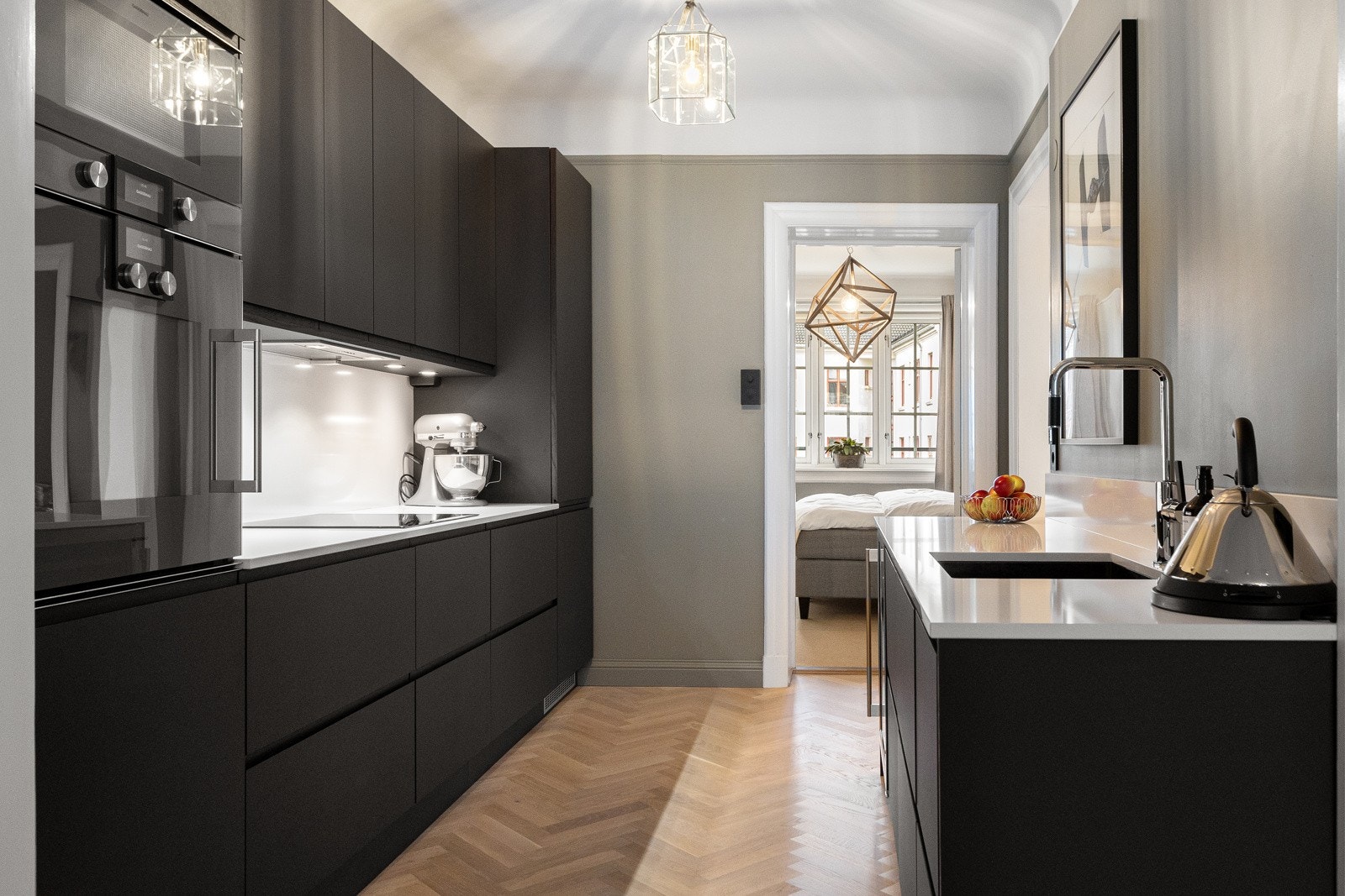 Her er det rikelig med benkeplass, samt gode oppbevaringsmuligheter i over- og underskap. I tillegg finnes en ekstra arbeidsbenk langs motsatt vegg, som ikke bare gir mer arbeidsflate, men også bidrar til god romfølelse og en harmonisk flyt videre inn mo Galleribilde