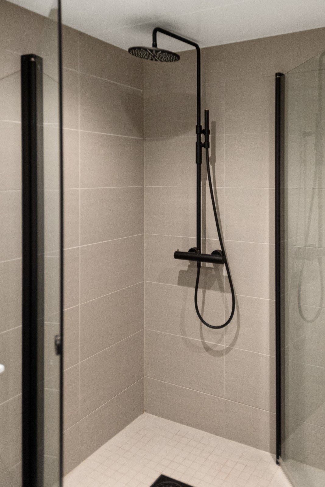 Matt sort dusjhjørne med innfellbare dusjvegger og regnfallsdusj. Galleribilde