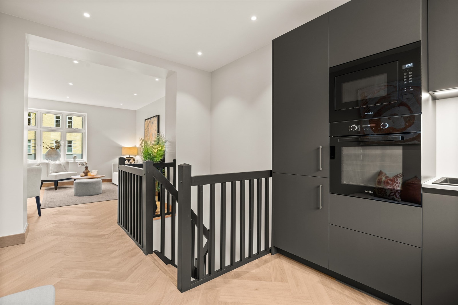 Kjøkkenet ligger i åpen løsning med stuen, men sonene skilles naturlig av trappegangen til kjelleretasjen. Galleribilde