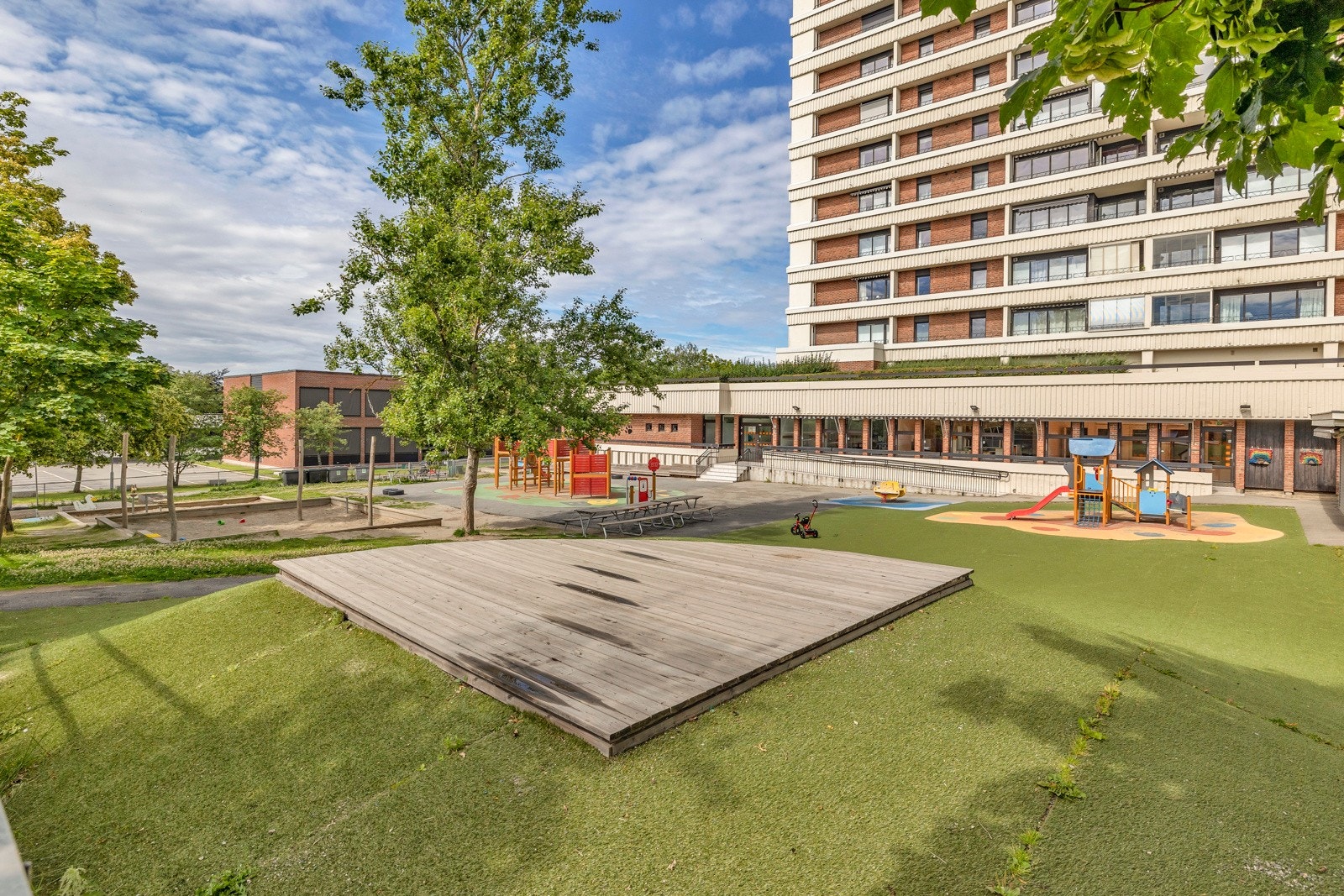 Tomten er pent opparbeidet med store, grønne områder, beplantninger, lekeplass og sittegrupper på baksiden av blokkene Galleribilde