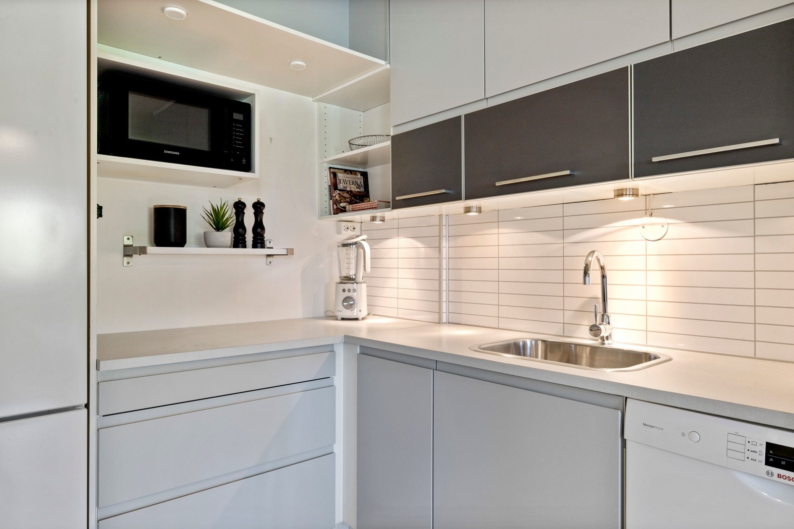 Kjøkkenet har en praktisk layout med innredning fra HTH, slette fronter og en benkeplate av laminat som gir god arbeidsflate Galleribilde