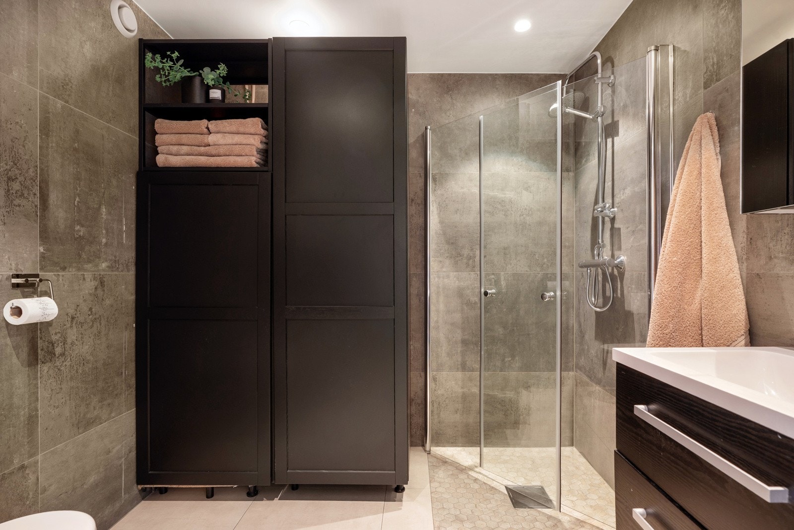 Leiligheten har to tidløse bad med store lyse fliser og varmekabler Galleribilde