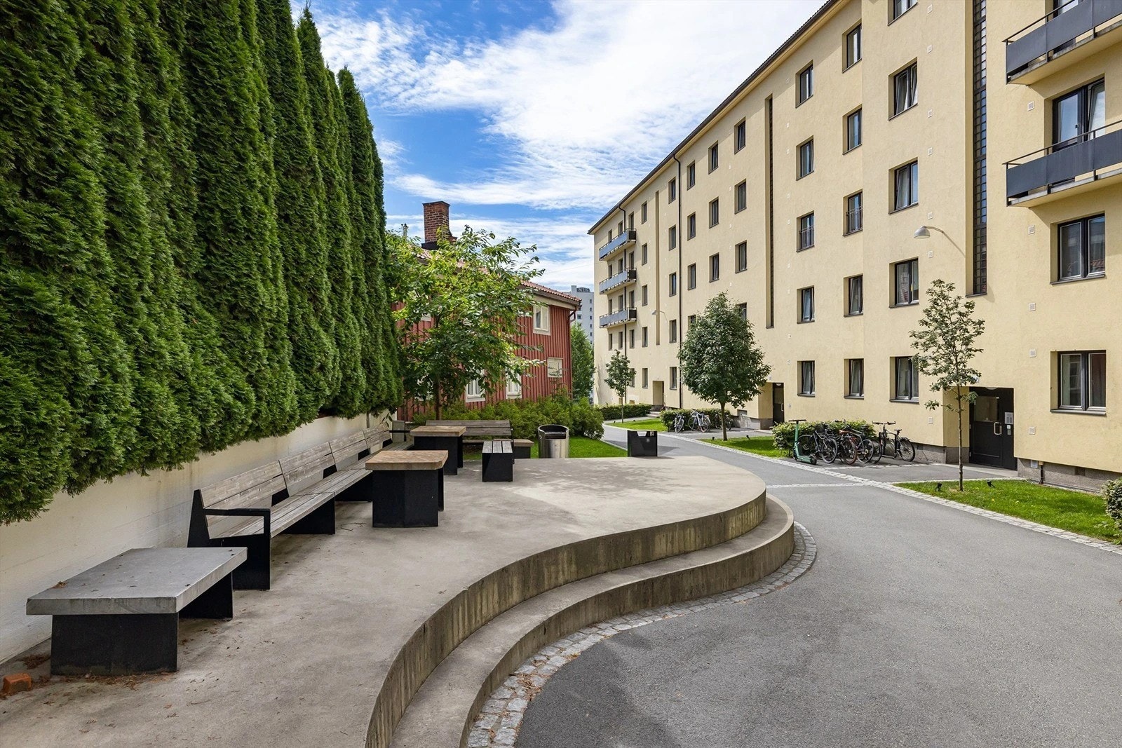 Borettslaget har et pent opparbeidet indre gårdsrom med plen, beplantning, sykkelparkering og internveier. Sommerbilde av gården. Galleribilde