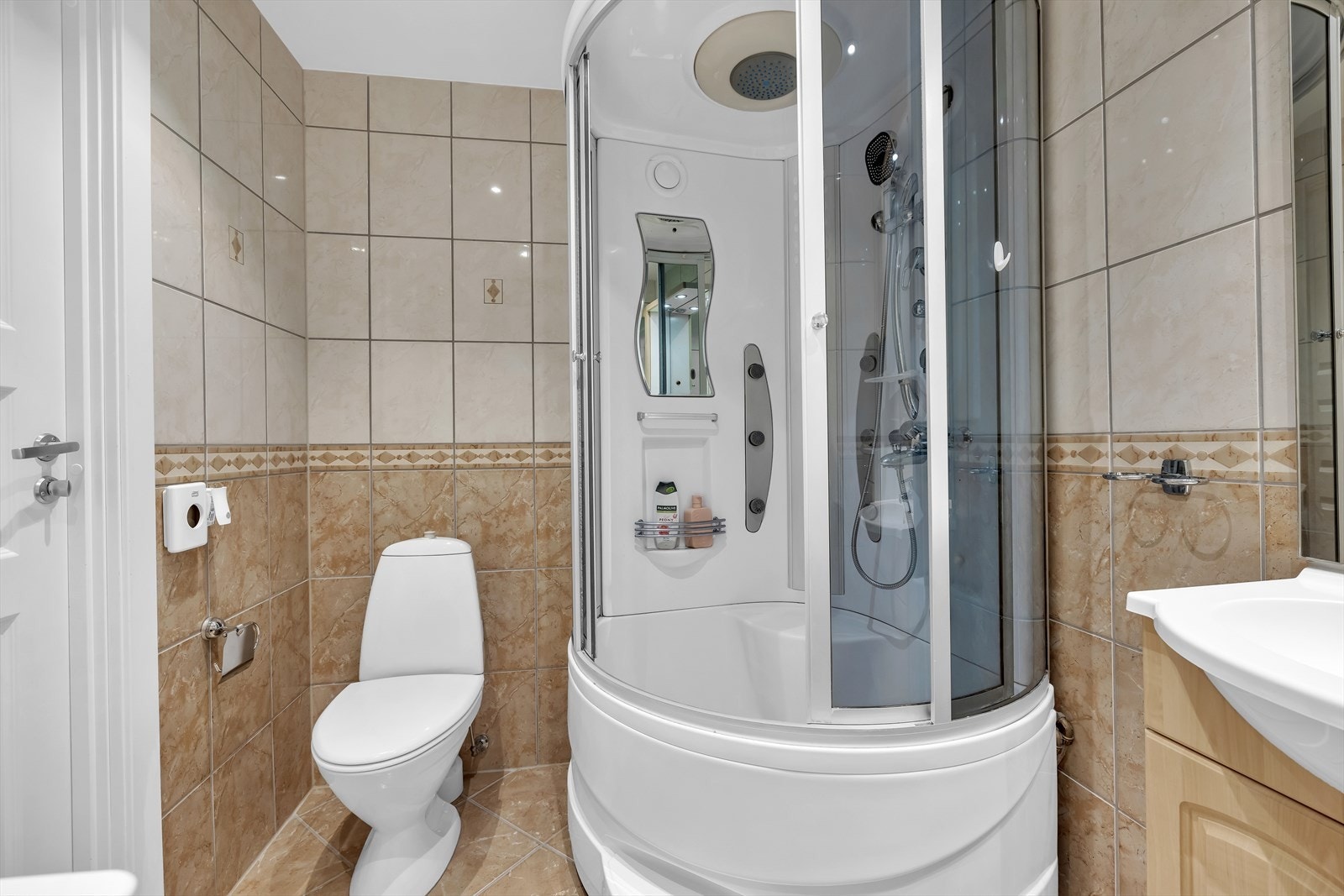 Romslig bad med dusjkabinett, wc, servant med underskap og overskap, speil og opplegg for vaskemaskin. Galleribilde