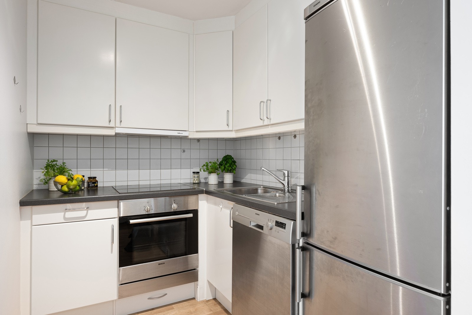 Kjøkkeninnredningen har glatte fronter og benkeplate i laminat med oppvaskkum i rustfritt stål. Integrerte hvitevarer inkluderer kjøl/fryseskap, oppvaskmaskin, keramisk platetopp og stekeovn Galleribilde