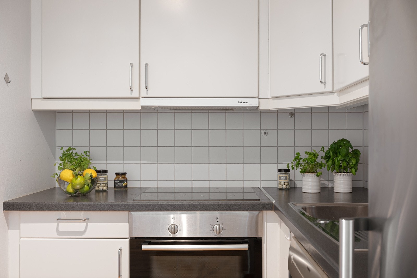 Kjøkkeninnredningen har glatte fronter og benkeplate i laminat med oppvaskkum i rustfritt stål. Integrerte hvitevarer inkluderer kjøl/fryseskap, oppvaskmaskin, keramisk platetopp og stekeovn Galleribilde