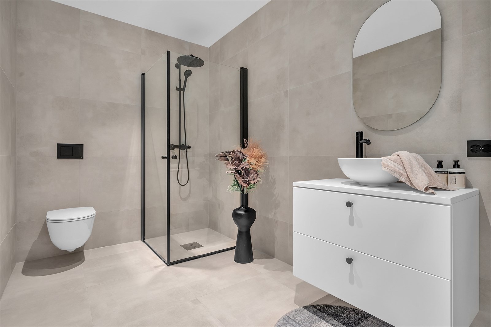 Baderommet er flislagt med vegghengt toalett, dusjhjørne og servant. Det er downlights i himling Galleribilde