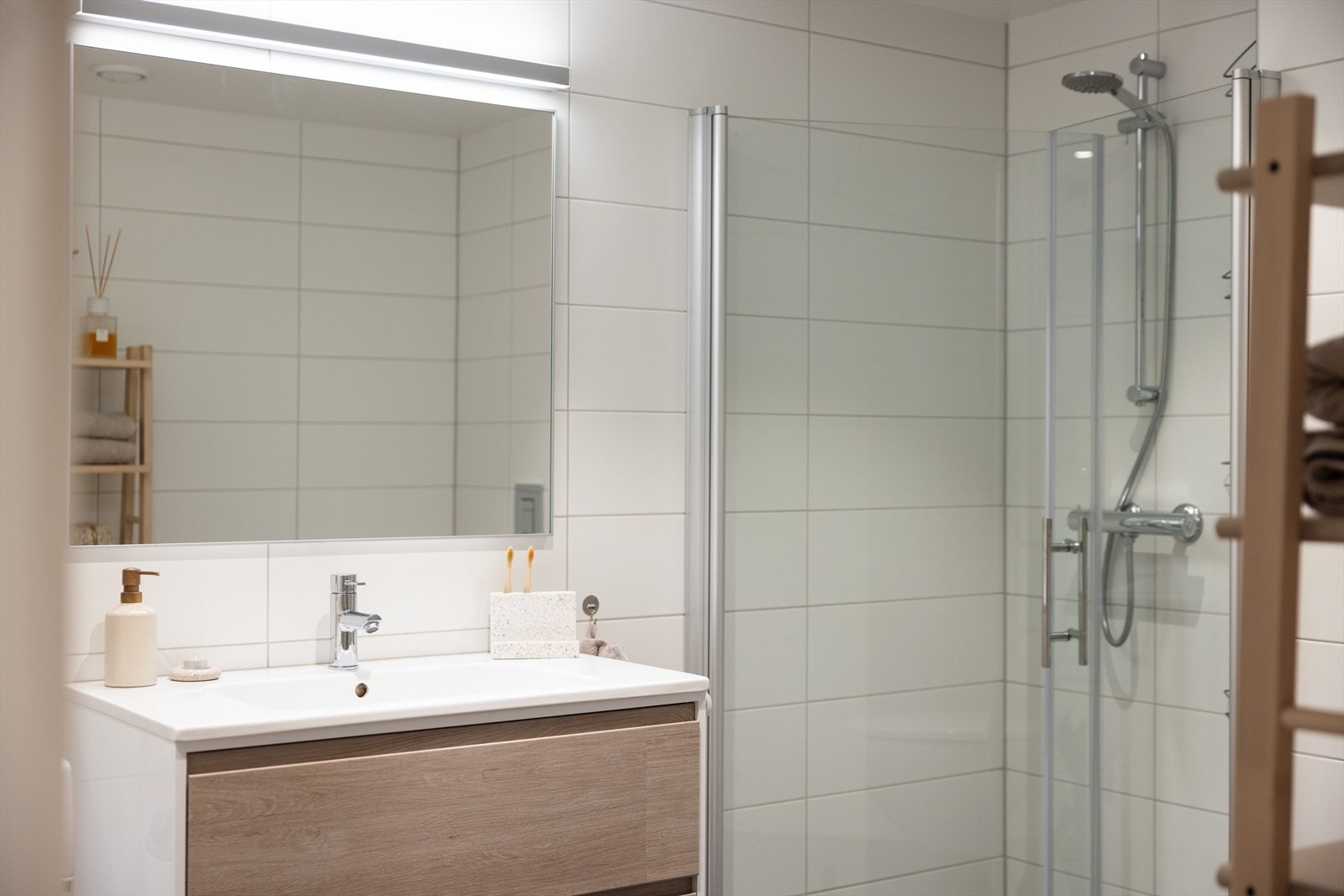 Badet er innredet med vegghengt klosett, servant på innredning og dusjvegger/hjørne. Galleribilde