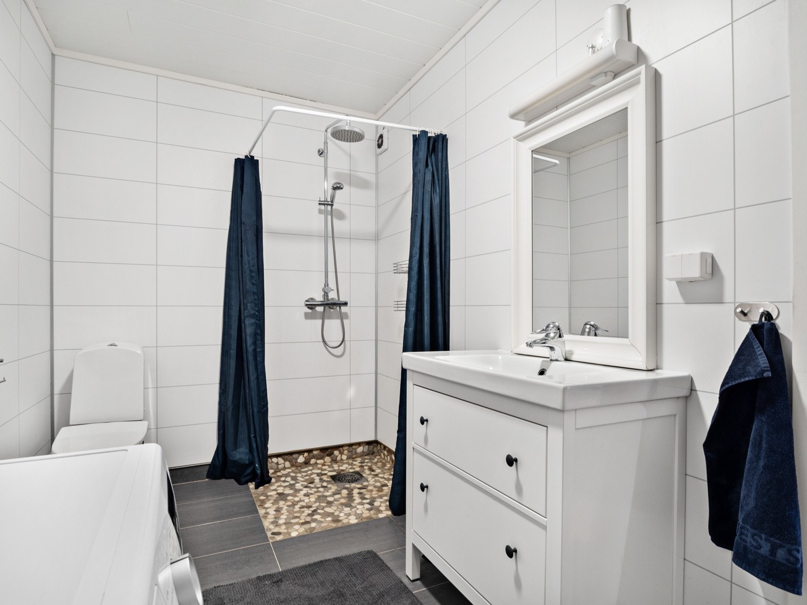 Baderommet har innredning, dusjhjørne, toalett og opplegg for vaskemaskin Galleribilde