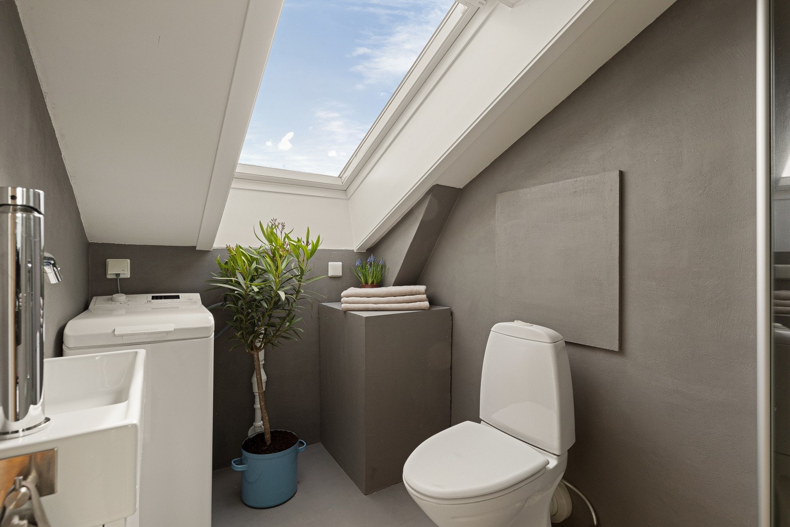 Glatt baderomsinnredning med heldekkende servant nedfeldt i underskap, toalett, dusjhjørne m/glassdører og opplegg for vaskemaskin. Galleribilde