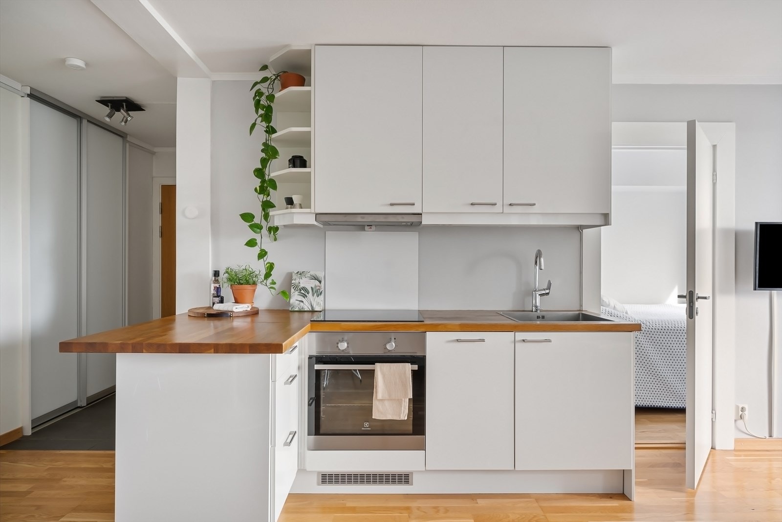 Pent, lyst kjøkken fra 2014 med belysning under overskap, heltre benkeplate og integrerte hvitevarer. Galleribilde