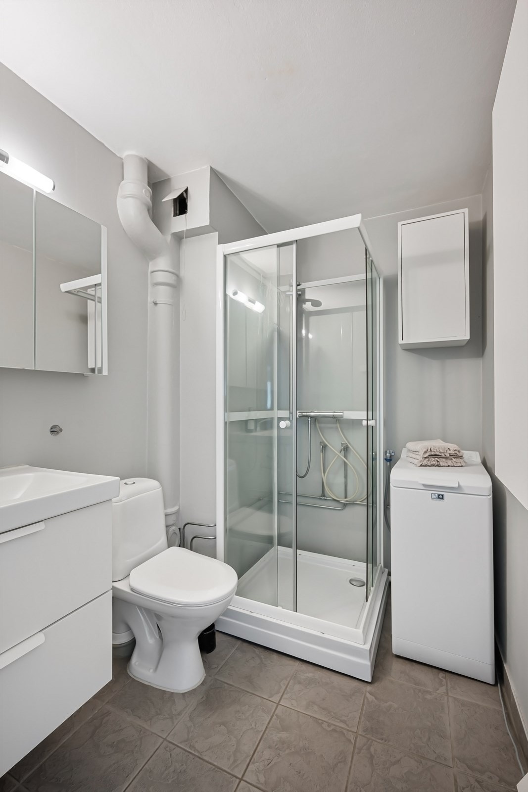 Badet har speilskap, servant med skuffer, dusj, toalett, overskap og opplegg for vaskemaskin. Det er i tillegg fellesvaskeri. Galleribilde