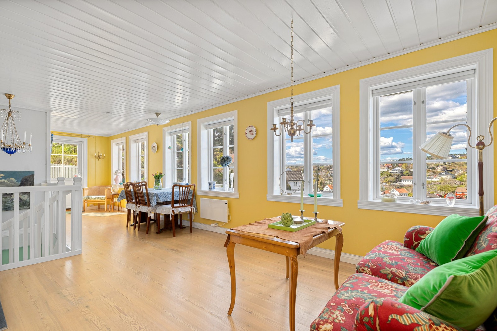 Dagslyset strømmer inn til den langstrakte stuen via mange, store vinduer. Galleribilde