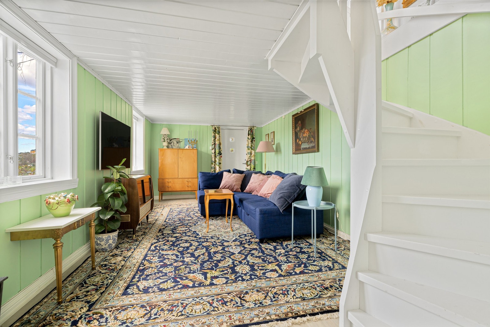 Fra stuen i 1. etasje går det en hvitmalt, klassisk trapp ned til en lys og koselig tv-stue i underetasjen. Stuen har egen utgang til hagen. Galleribilde