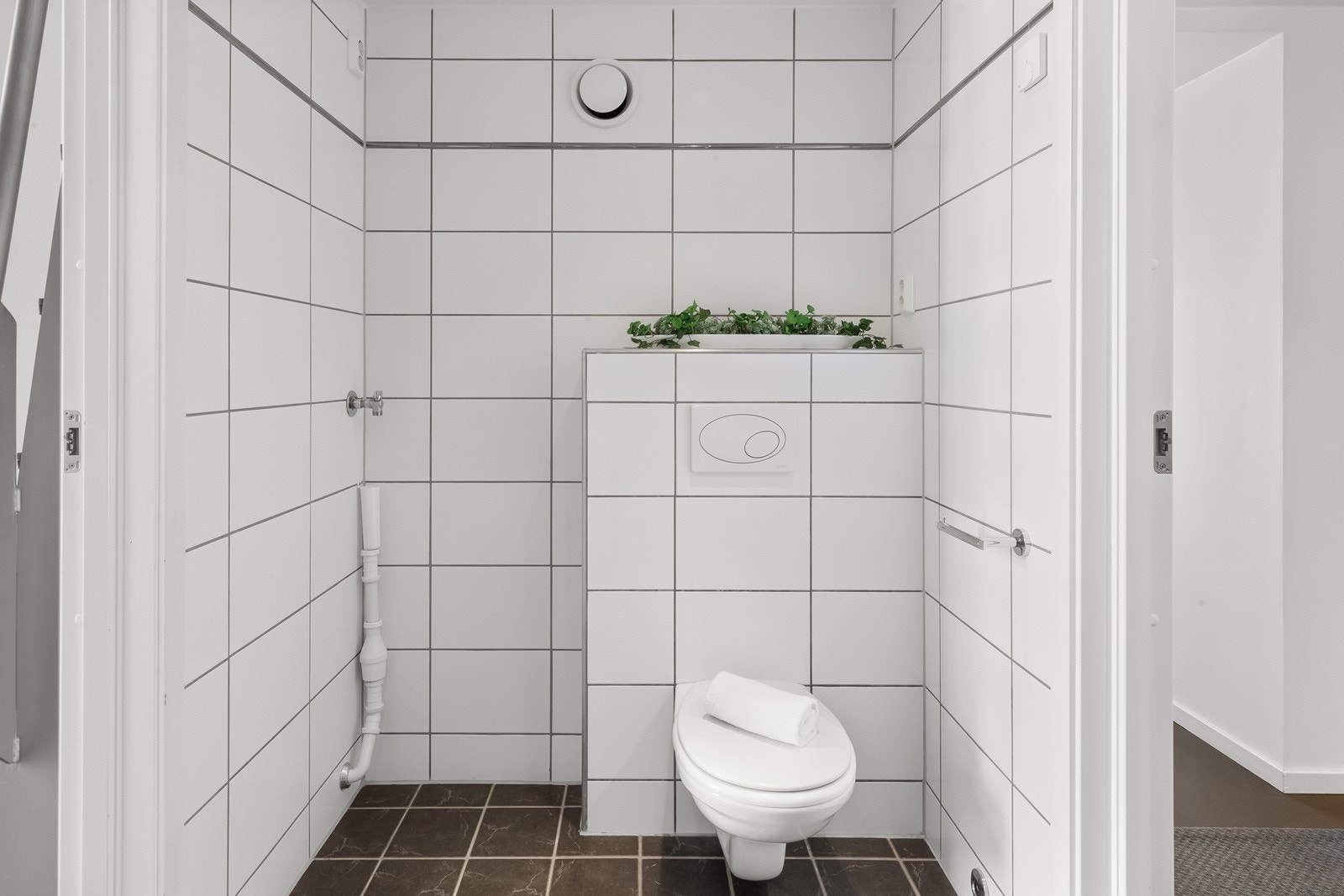 Dusjhjørne med innfellbare dører i glass, veggmontert klosett og moderne servantskap med heldekkende servant Galleribilde